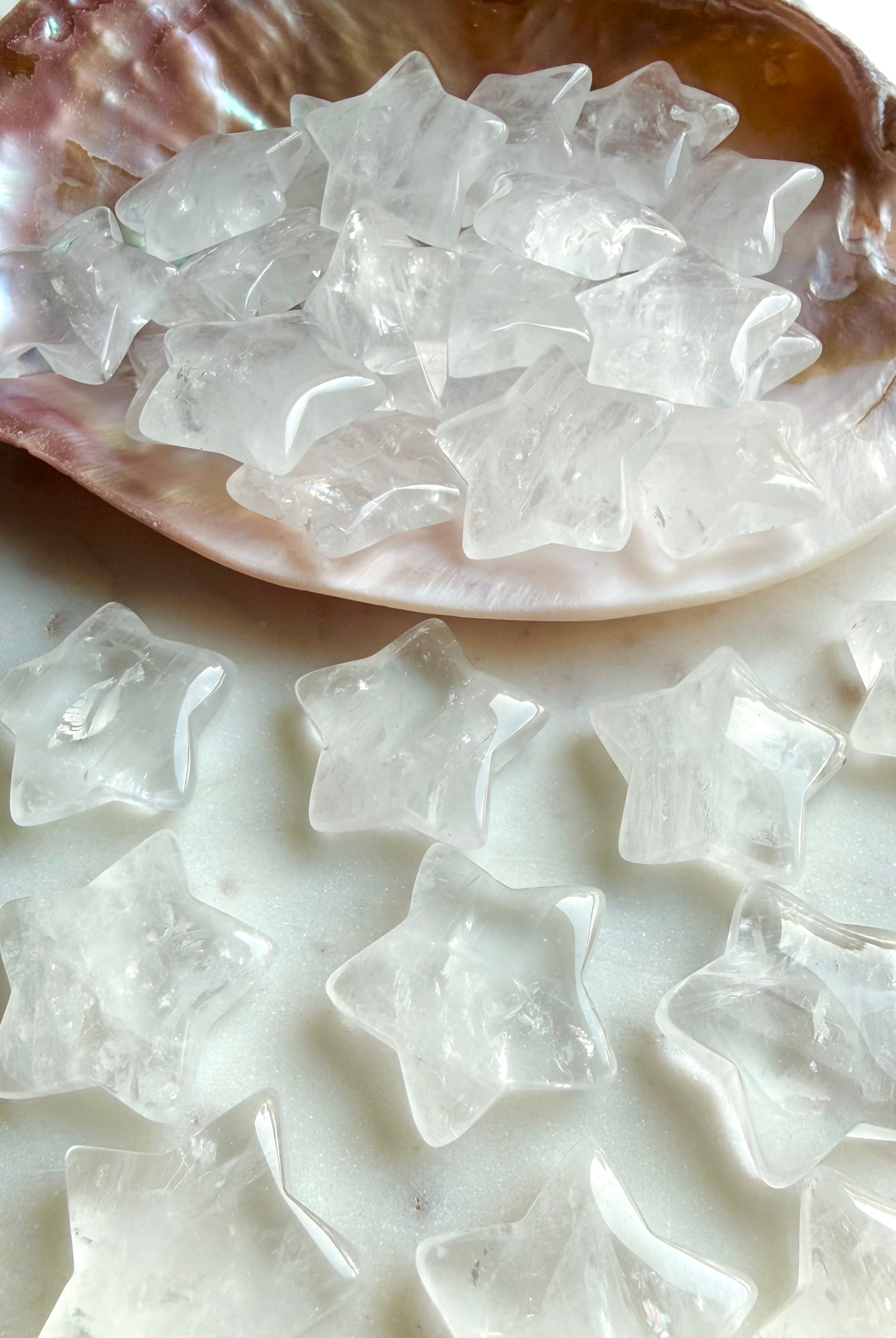 Clear Quartz stars spilling from a shell onto granite surface, celestial crystals for chakra healing and altar décor