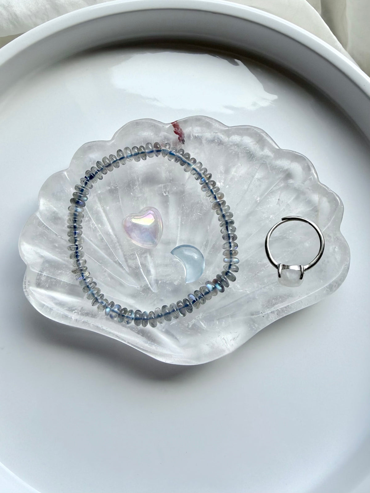 Clear Quartz scallop shell jewelry dish holding a ring and small crystal, polished gemstone bowl for jewelry storage and altar decor