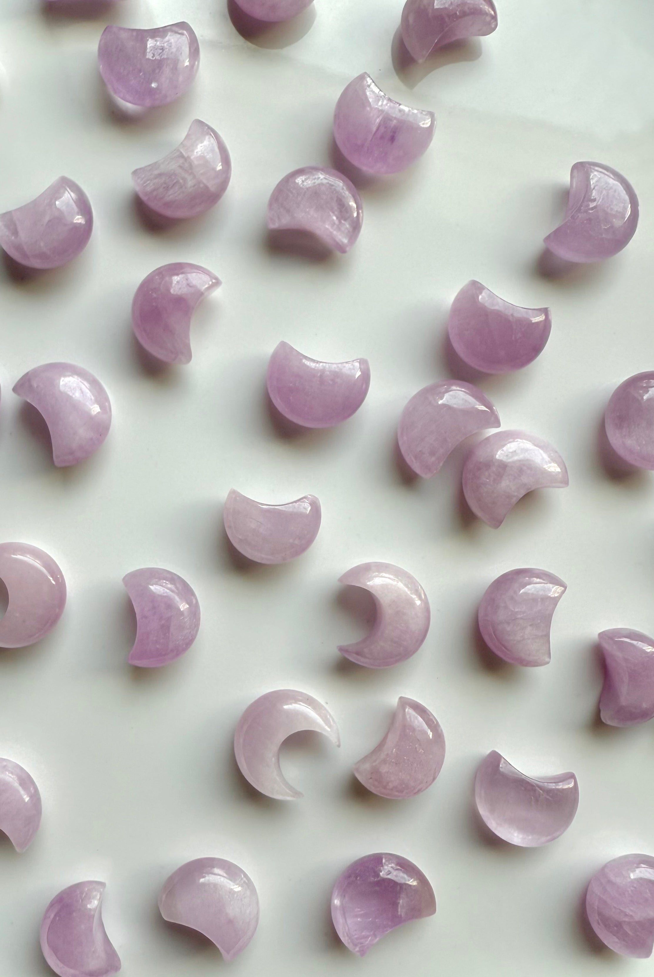 Mini Pink Kunzite crescent moons on a white plate — soft pink crystal carvings for heart-centered healing & emotional harmony.
