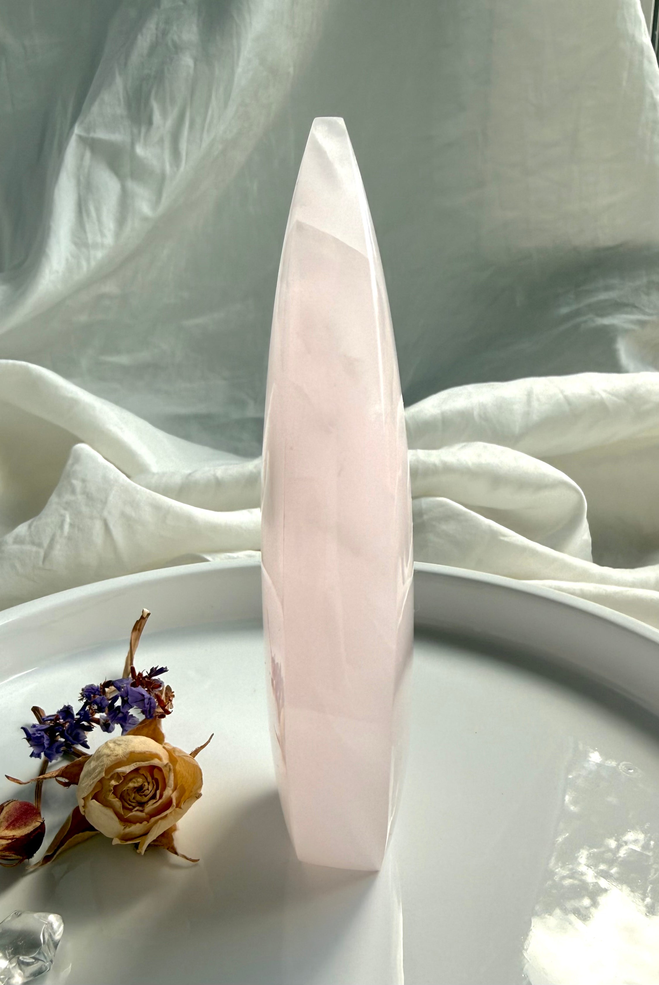 Side view of Mangano Calcite flame carving showing slender profile, soft translucency and polished crystal surface