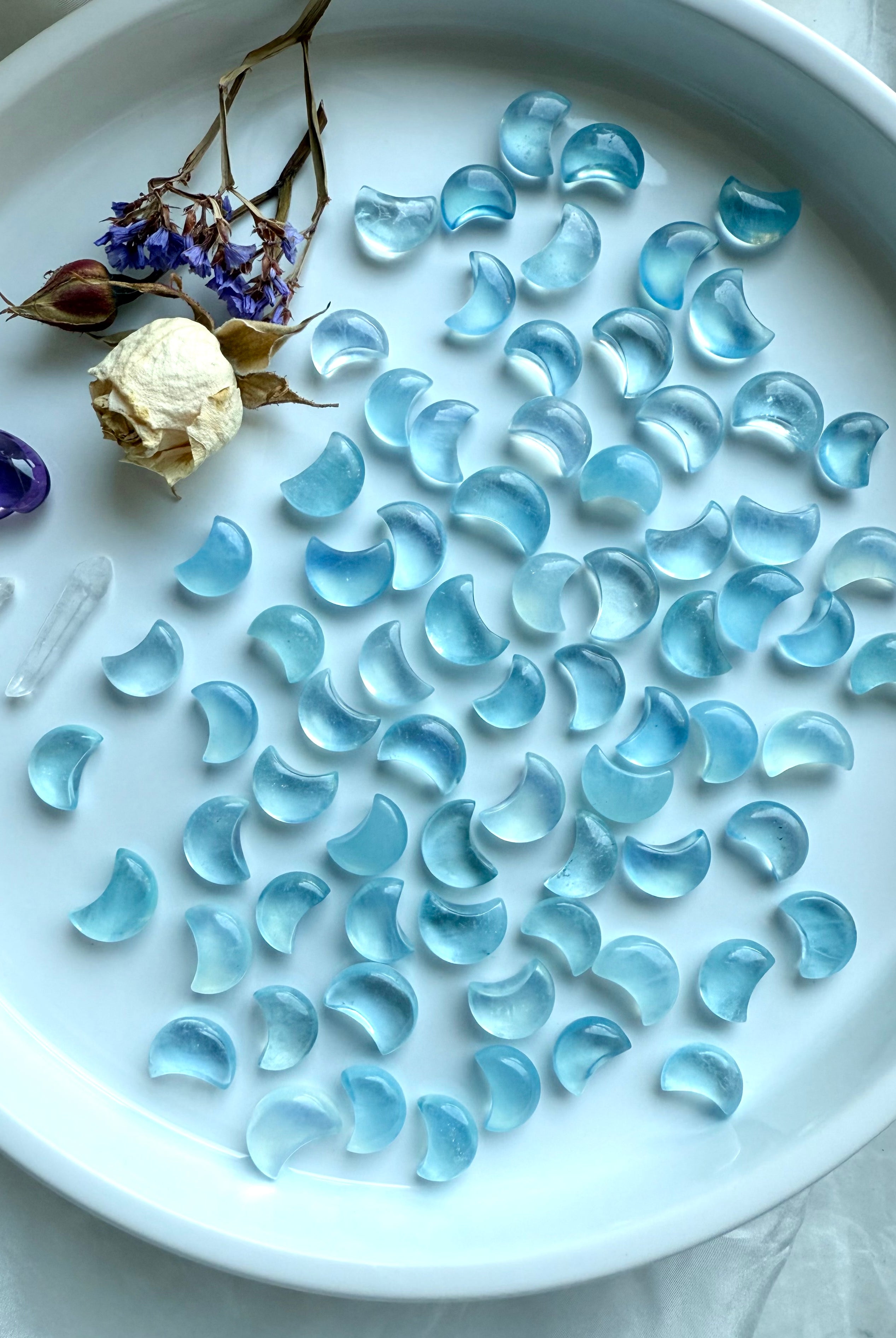 Celestial display of Aquamarine moon carvings with dried botanicals and amethyst heart — gemstone moons for March birthstone gifts and crystal healing