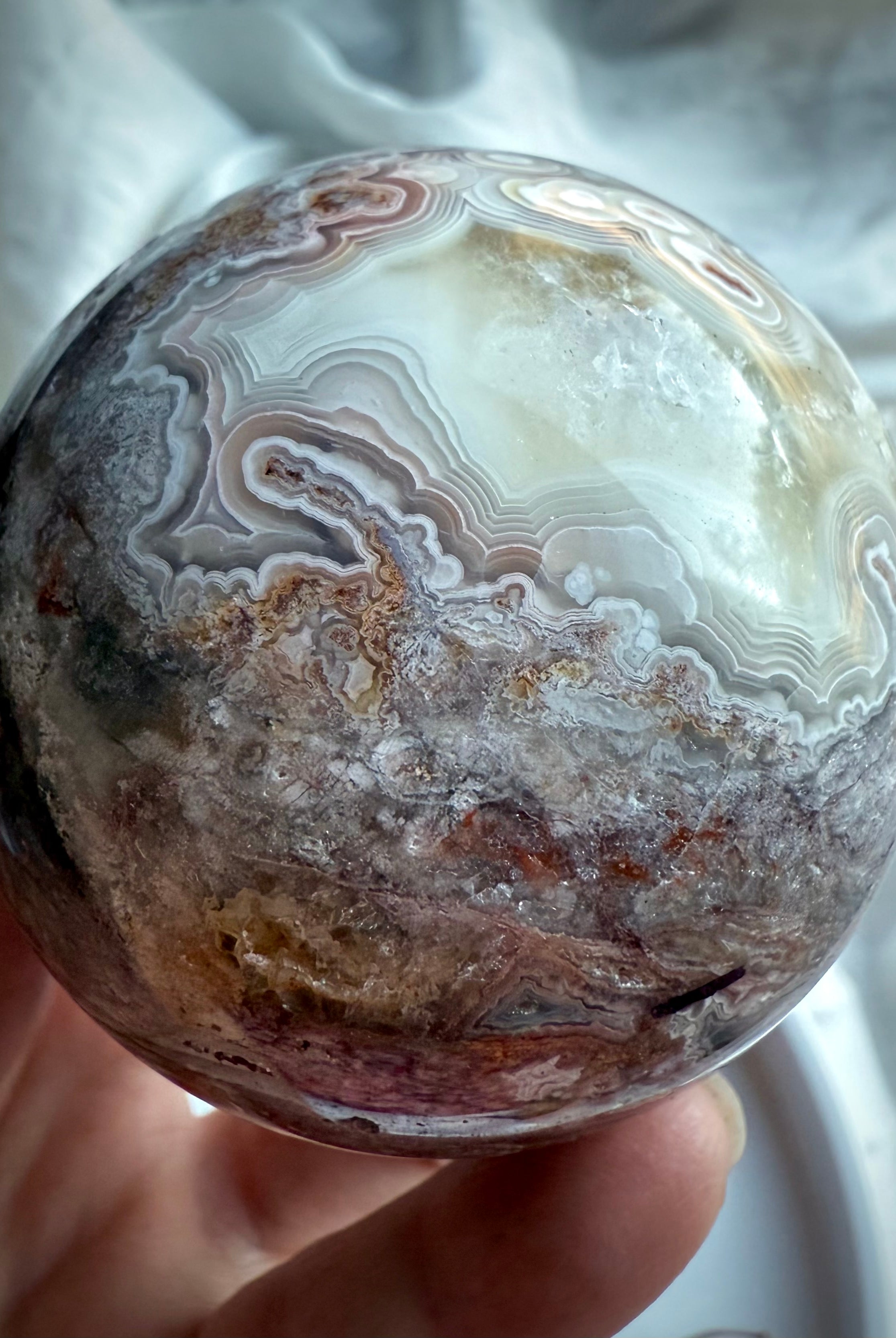 High-quality crazy lace agate sphere with crystalline druzy pocket and fine white, beige, and pink agate bands