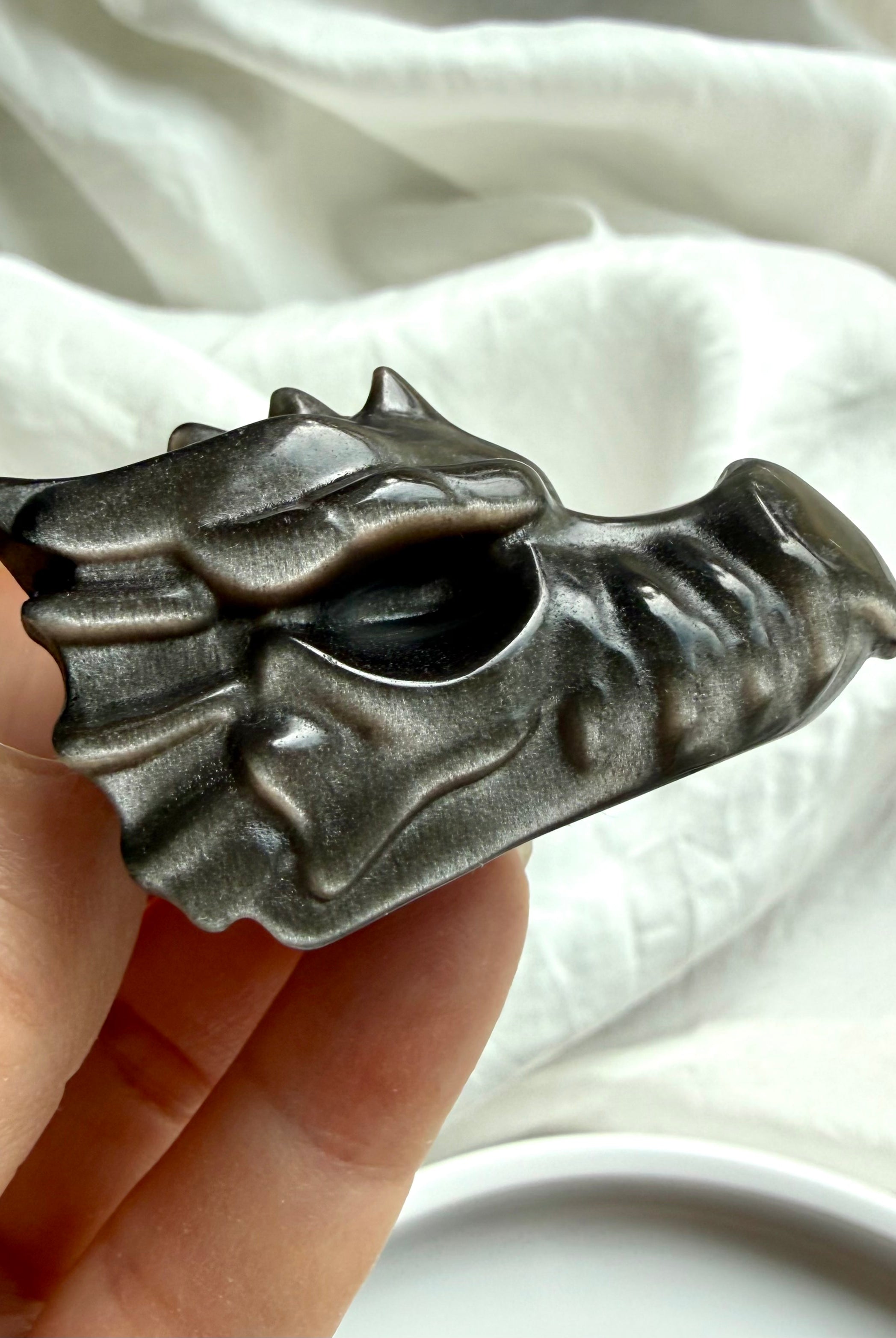 silver sheen obsidian dragon carving with glossy black finish and subtle metallic flash, crystal for protection shadow work and grounding energy