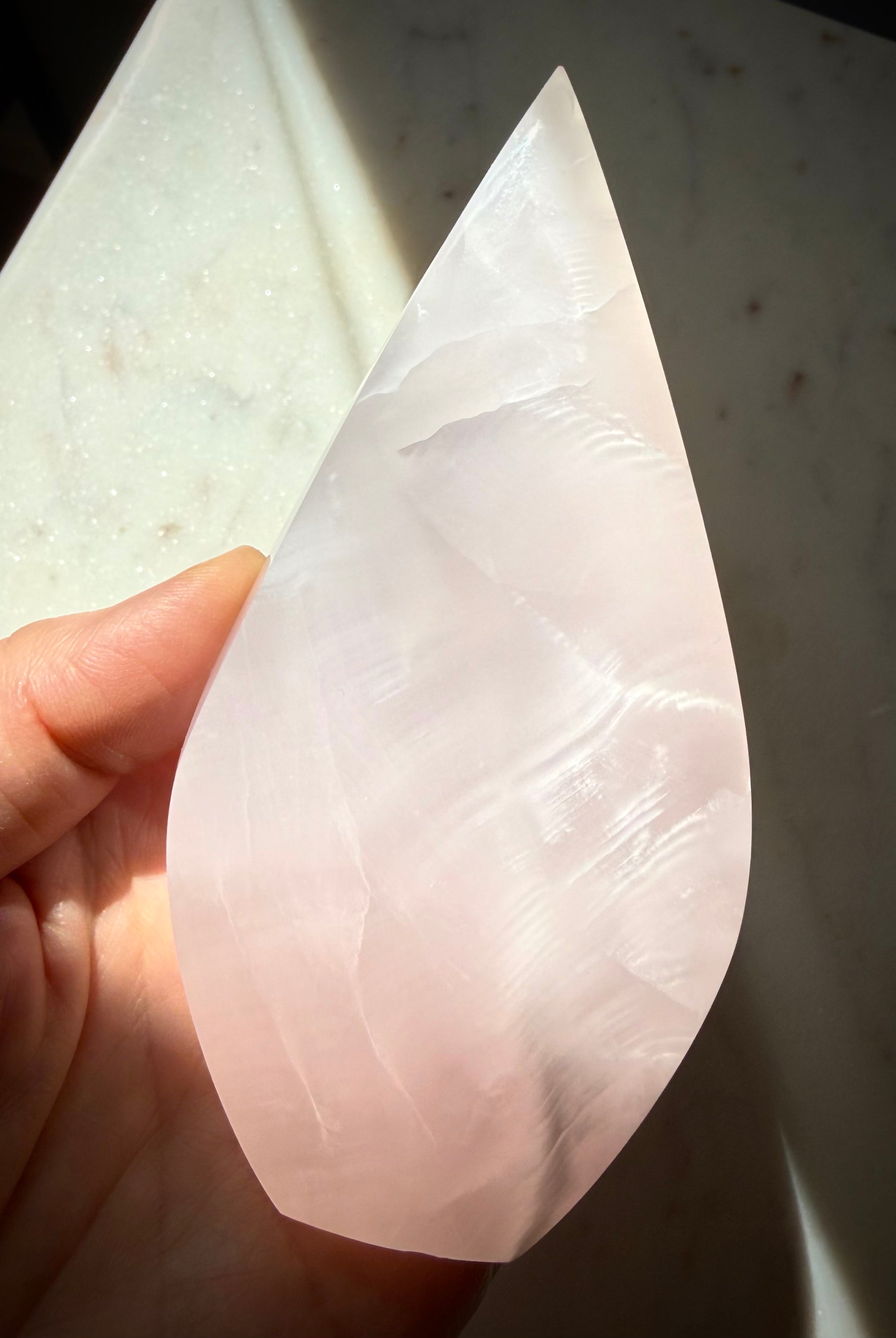 Backlit Mangano Calcite flame crystal revealing soft translucency, internal formations and luminous pink glow
