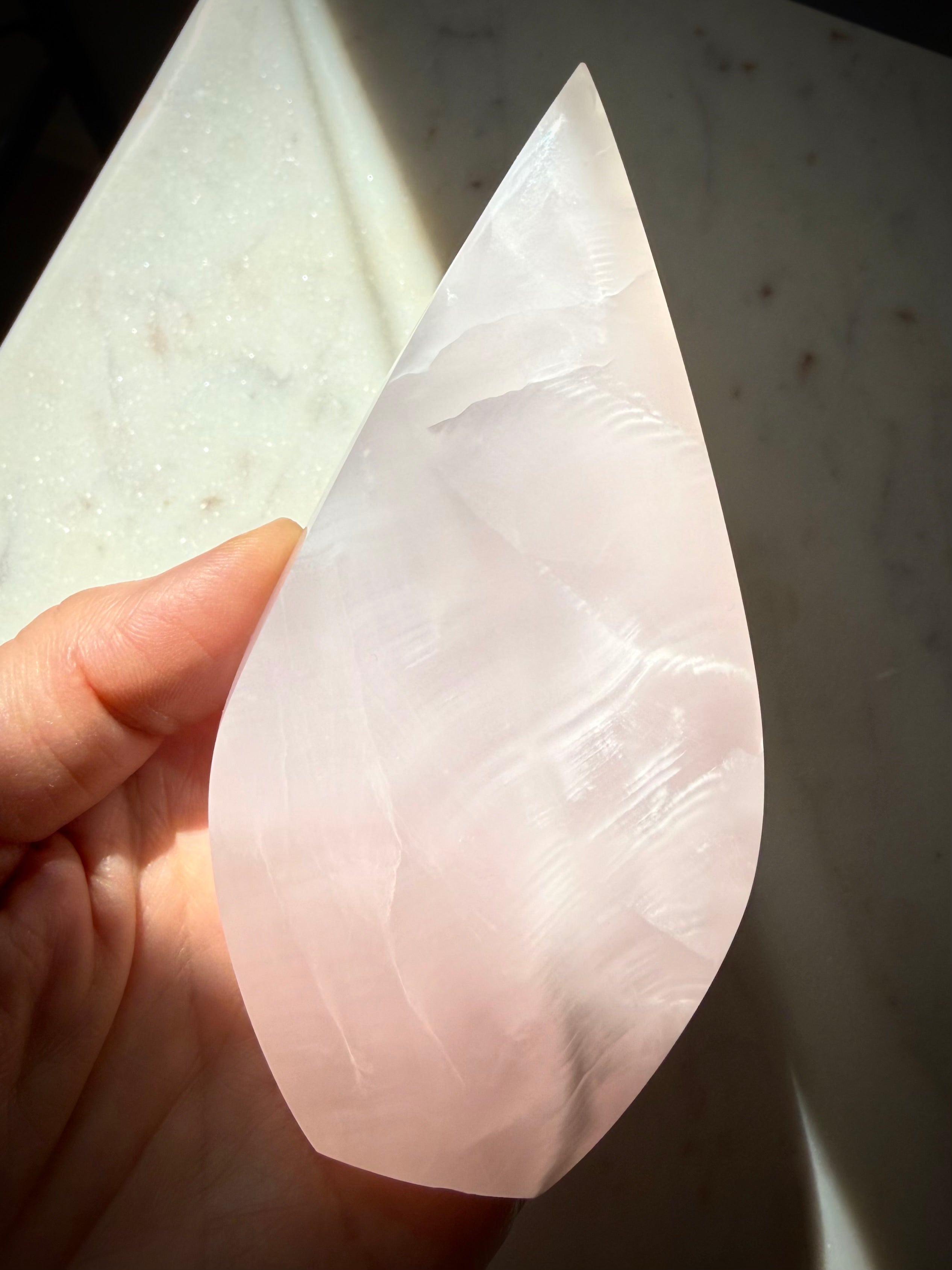 Backlit Mangano Calcite flame crystal revealing soft translucency, internal formations and luminous pink glow