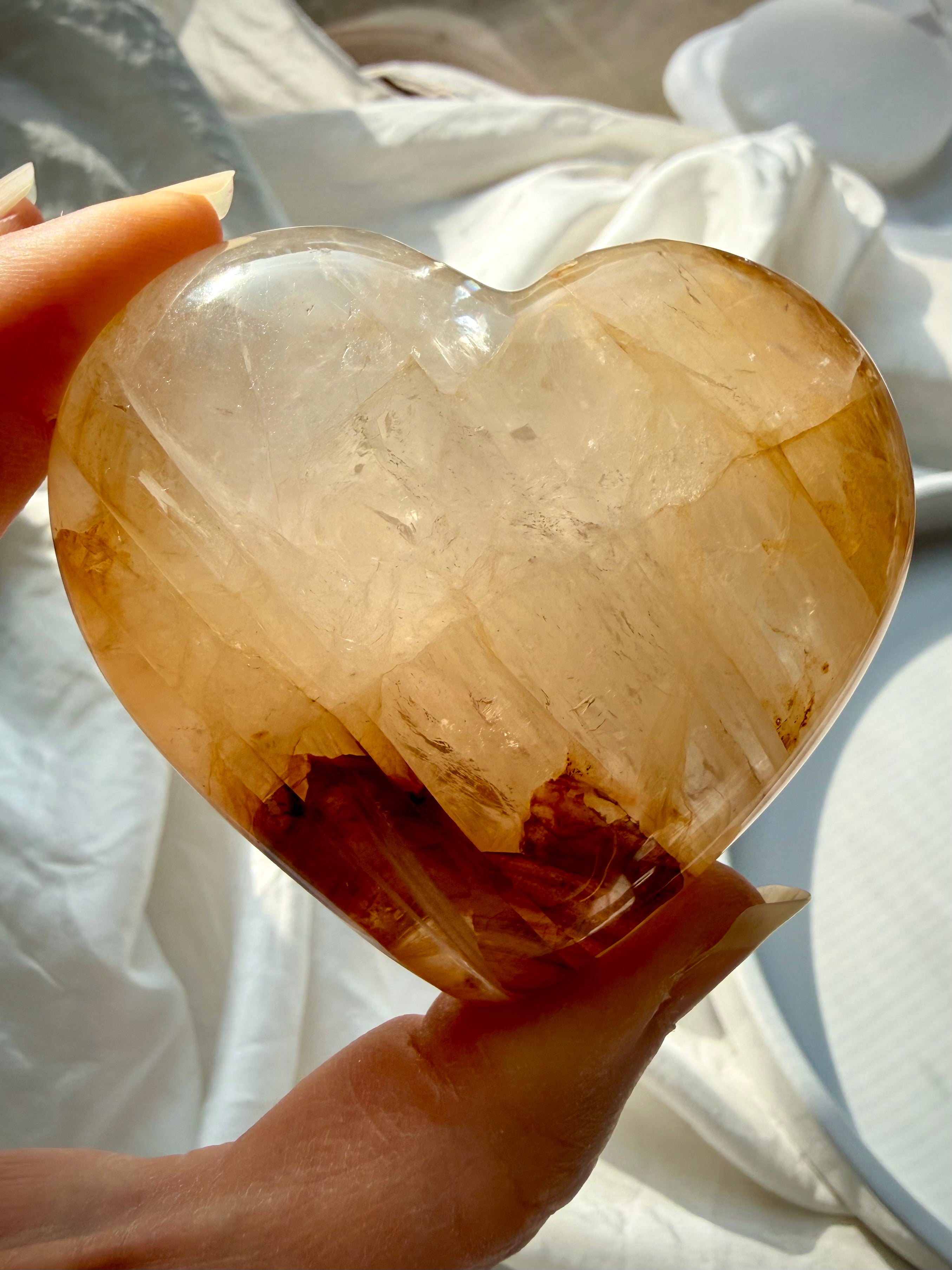 Golden Healer quartz heart held in palm with warm golden hues and natural iron inclusions for confidence and Solar Plexus healing