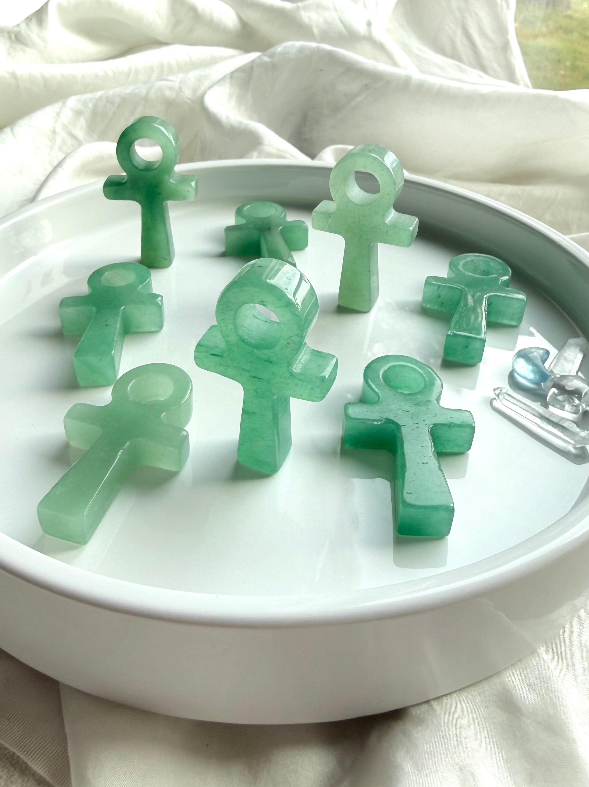 Polished Green Aventurine ankh carvings on white tray – small crystal ankhs symbolizing life force, abundance, and spiritual renewal