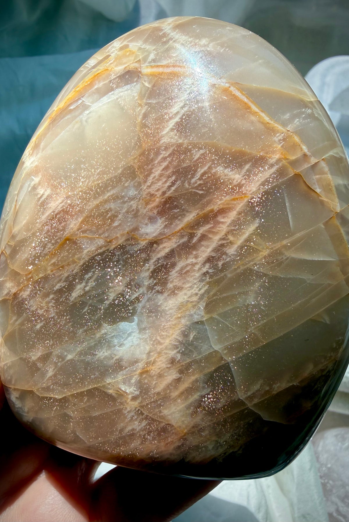 Reverse side of Peach Moonstone freeform with abundant golden Sunstone shimmer sparkling across the polished surface