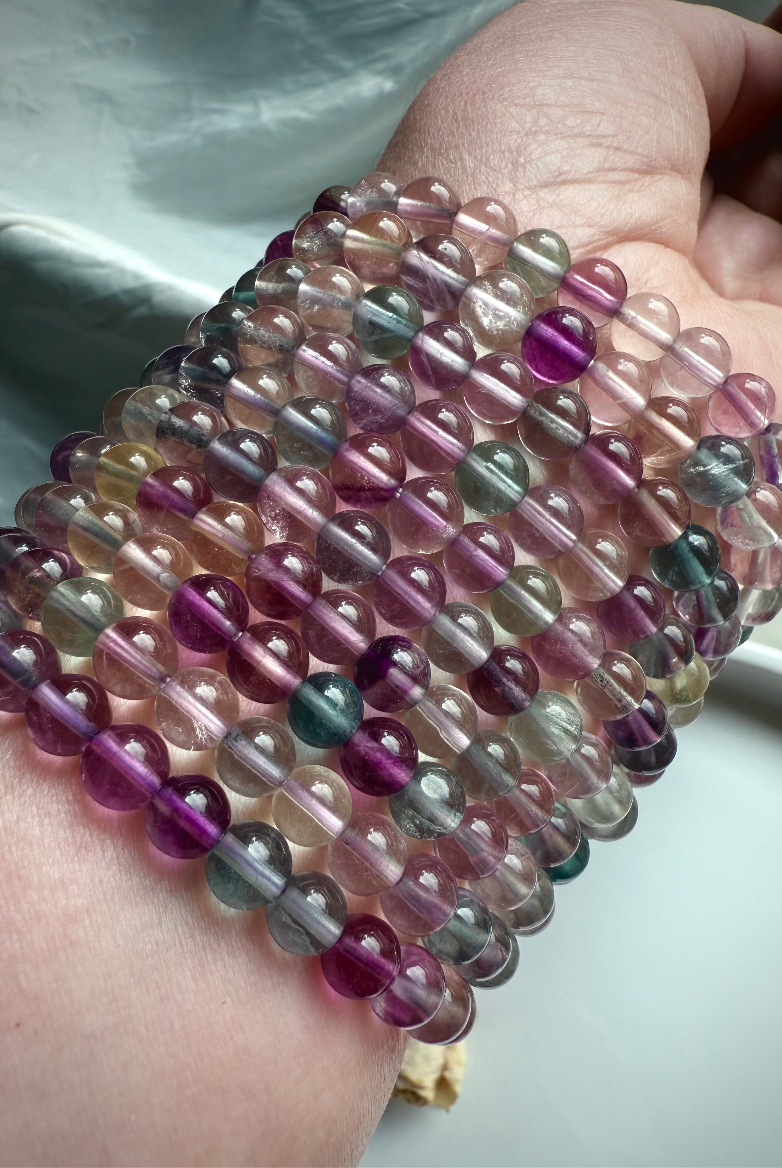 Stacked rainbow fluorite bracelets displaying natural color variation in purple, green, and clear fluorite crystals