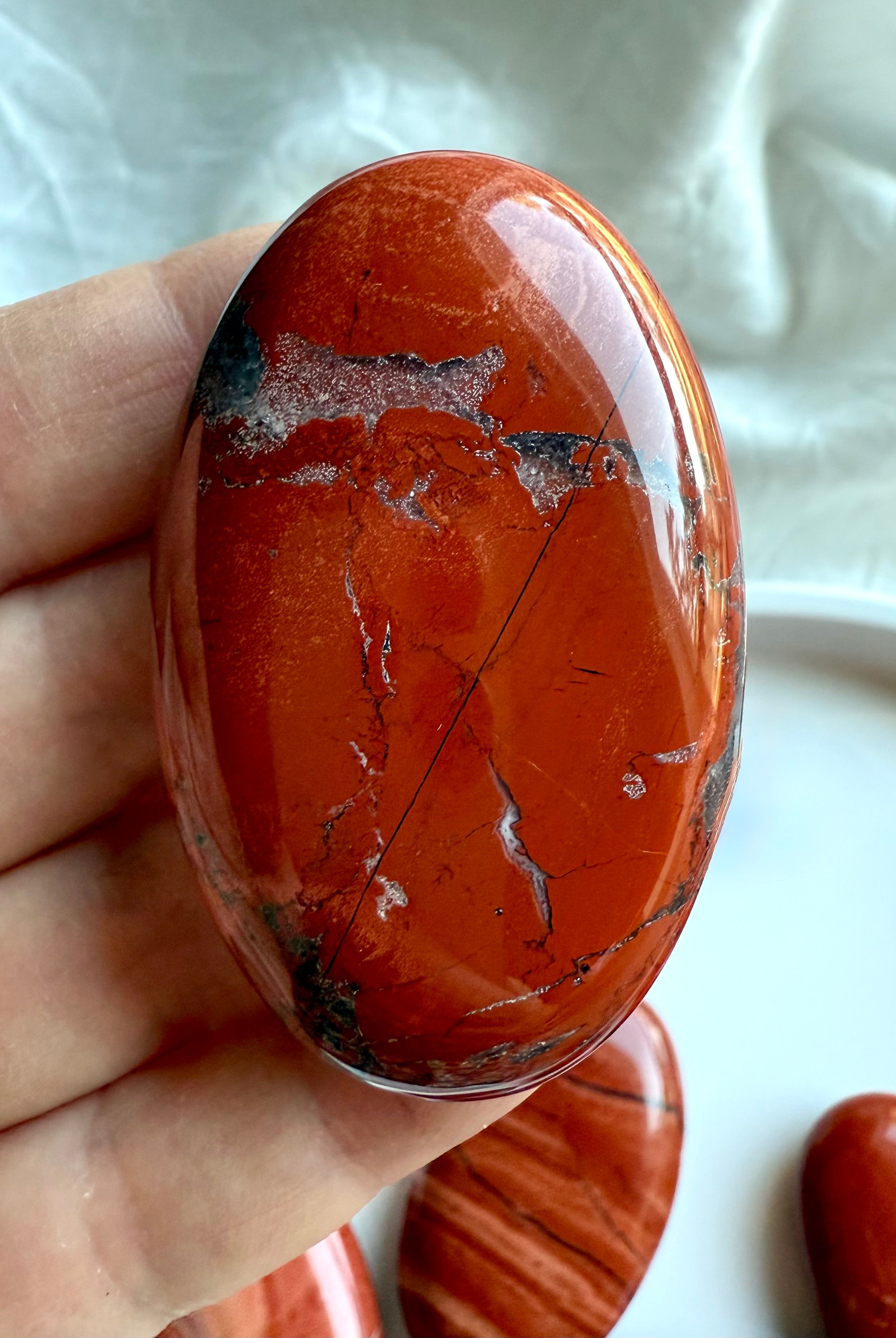 Detailed view of Red Jasper palm stone — earthy red crystal with natural patterns and inclusions.