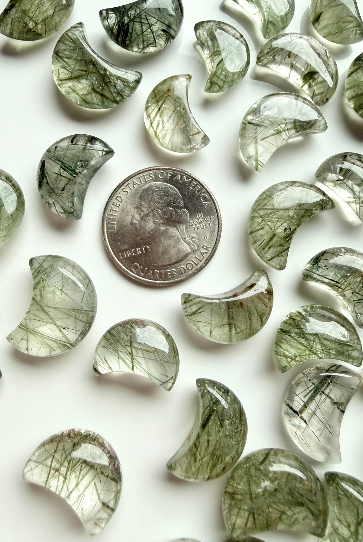 Green Tourmaline in Quartz moons with natural inclusions shown beside a coin for scale and size comparison