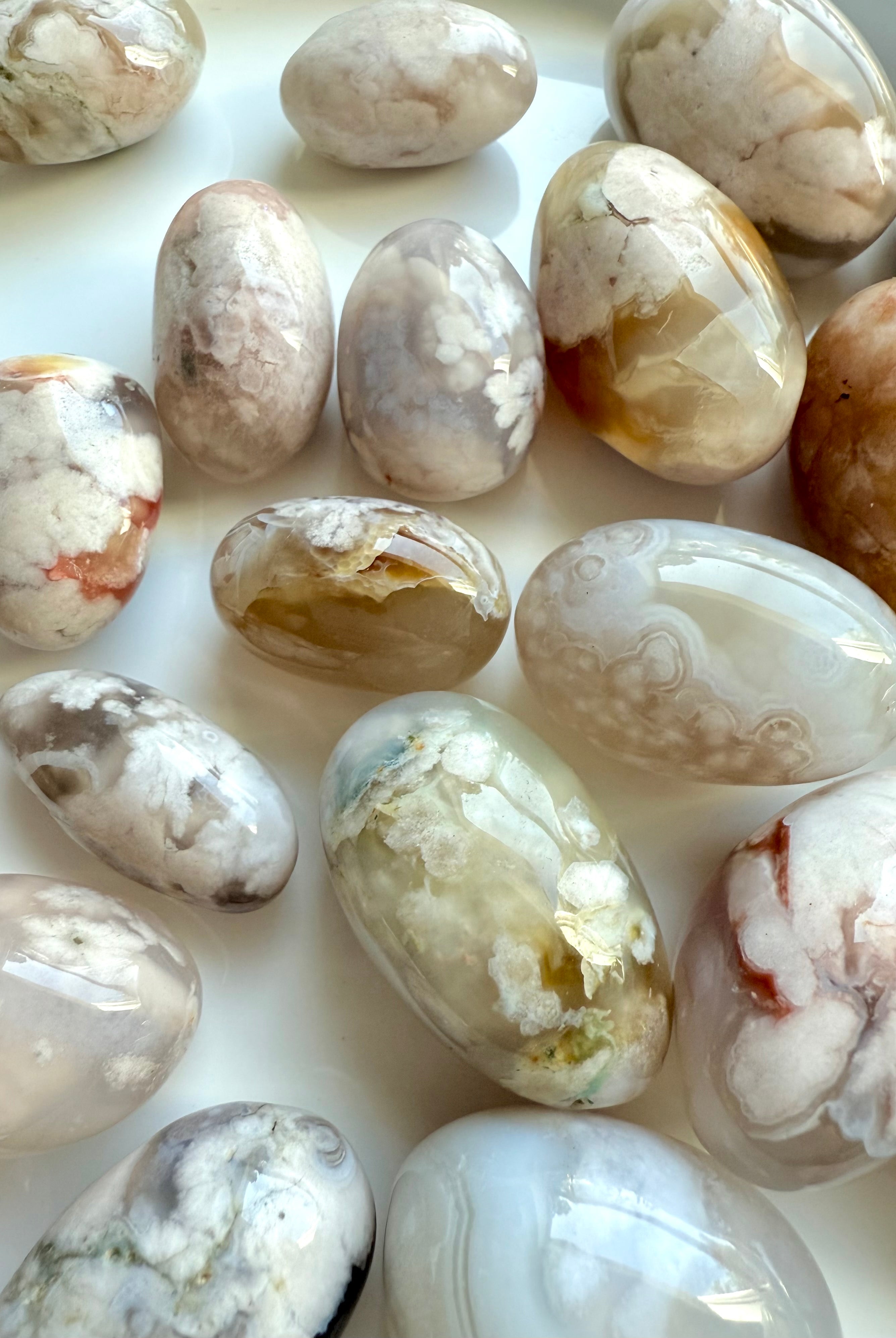 Close up of high quality Flower Agate tumbled stones with beautiful pastel colors on a white plate