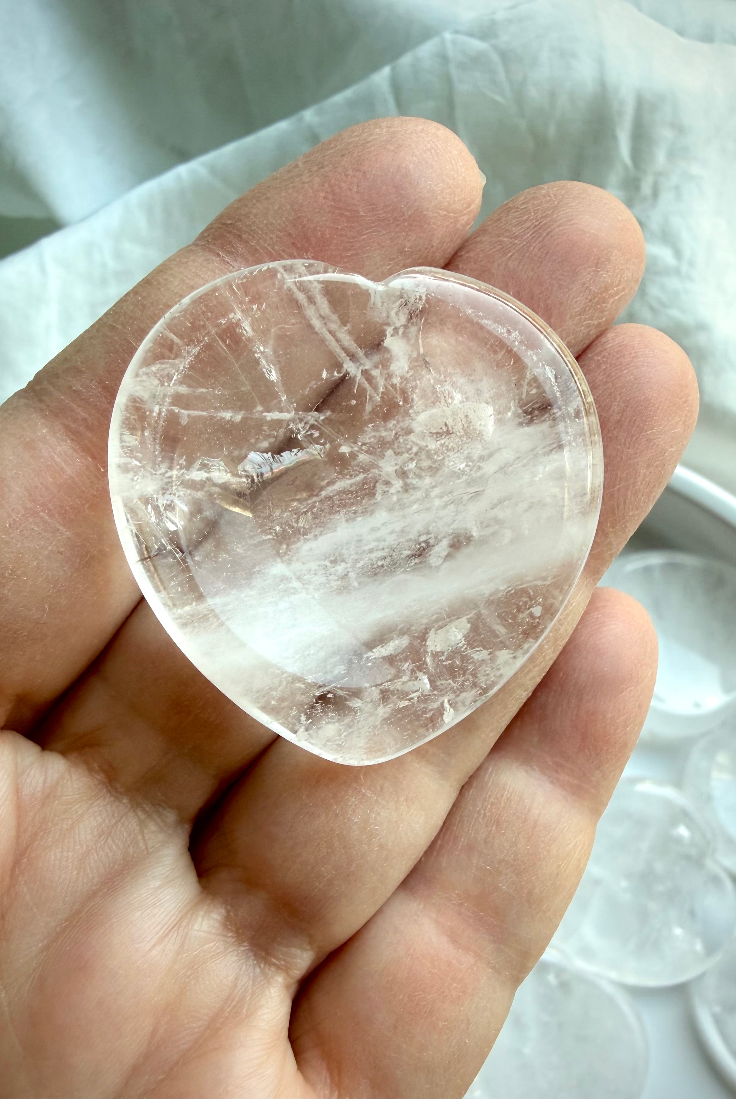 up close clear quartz heart stone held in hand for clarity focus and emotional balance