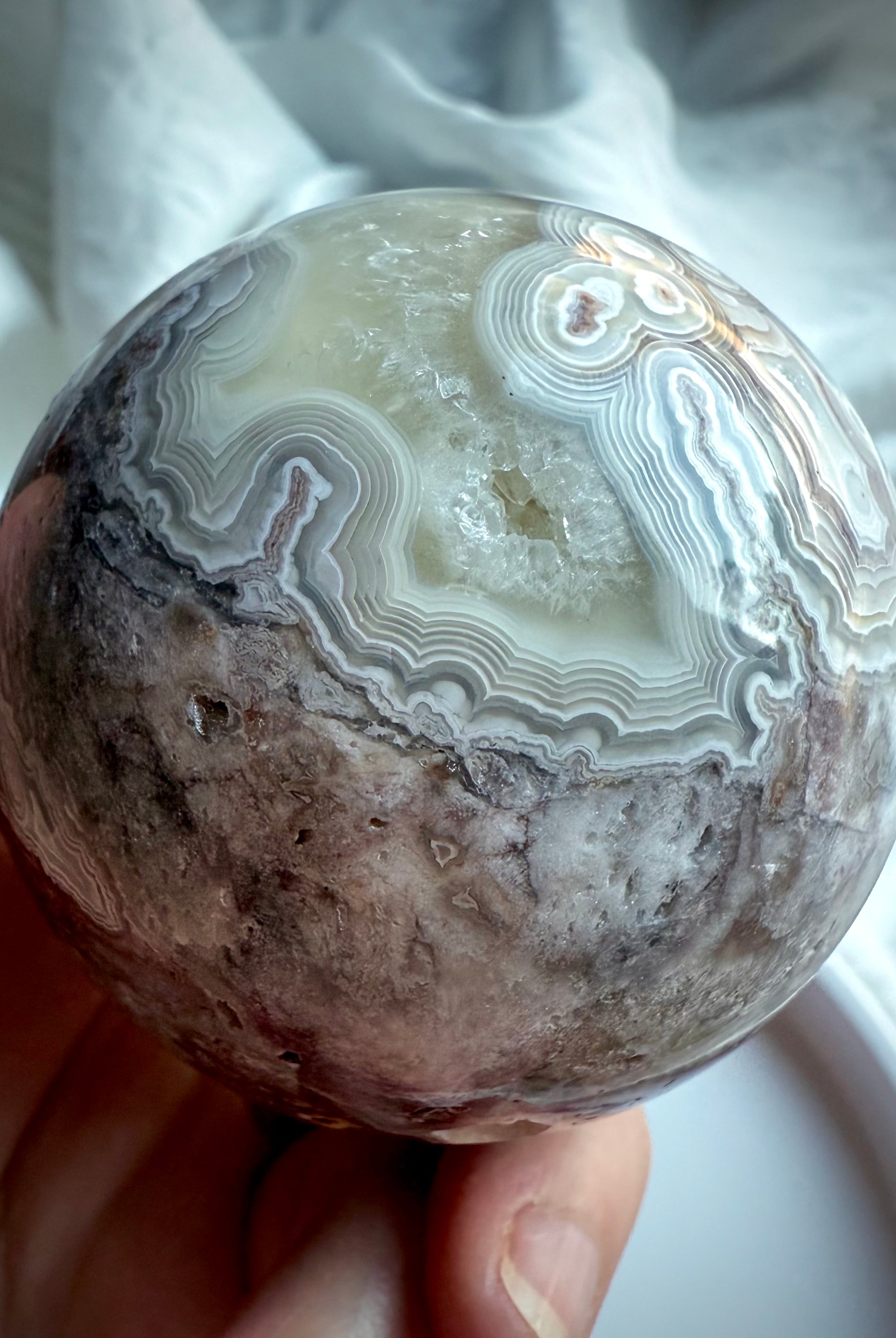 Detailed view of crazy lace agate sphere with earthy matrix and pale agate bands, perfect for grounding energy