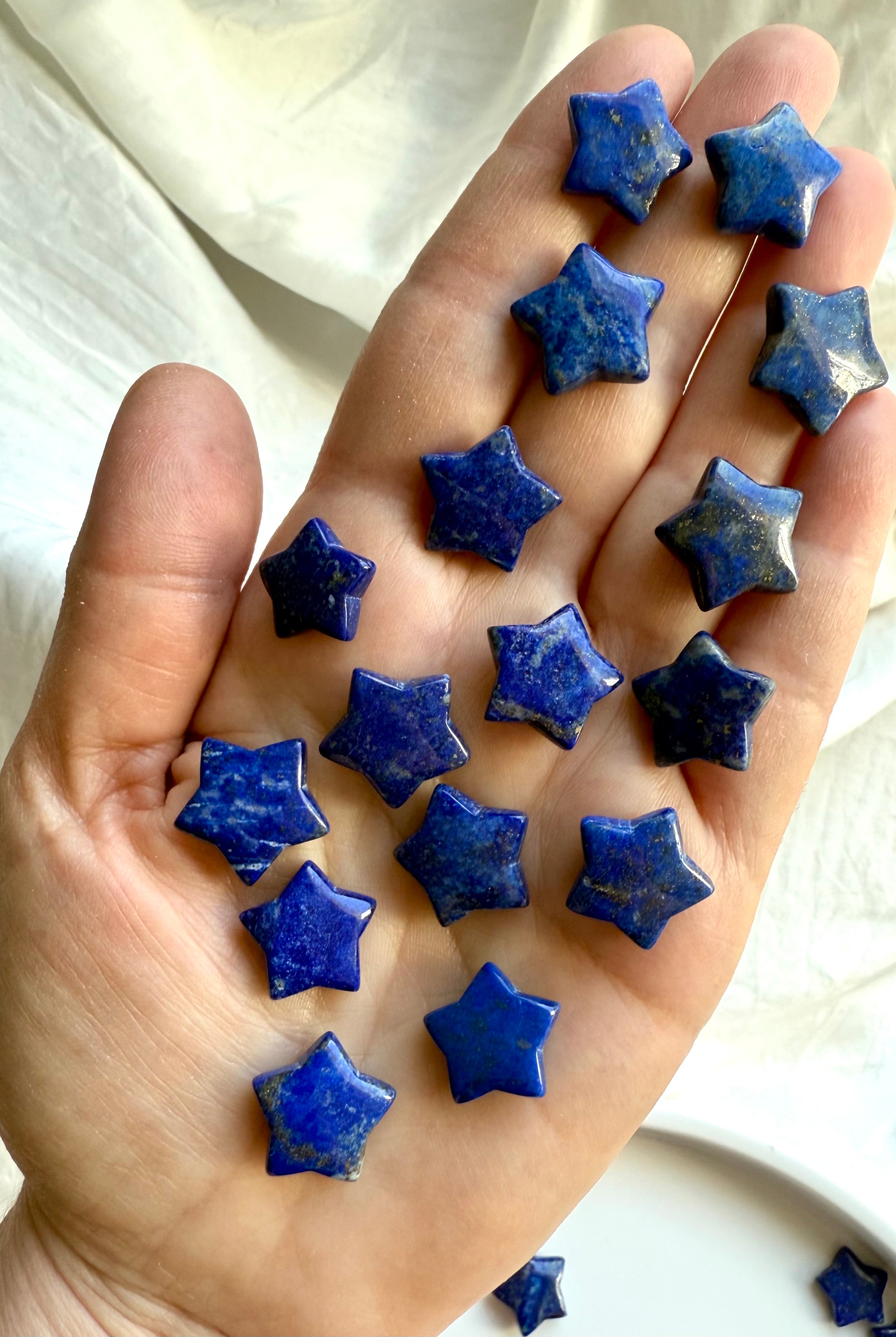 An array of blue Lapis Lazuli star crystals resting in open hand for scale