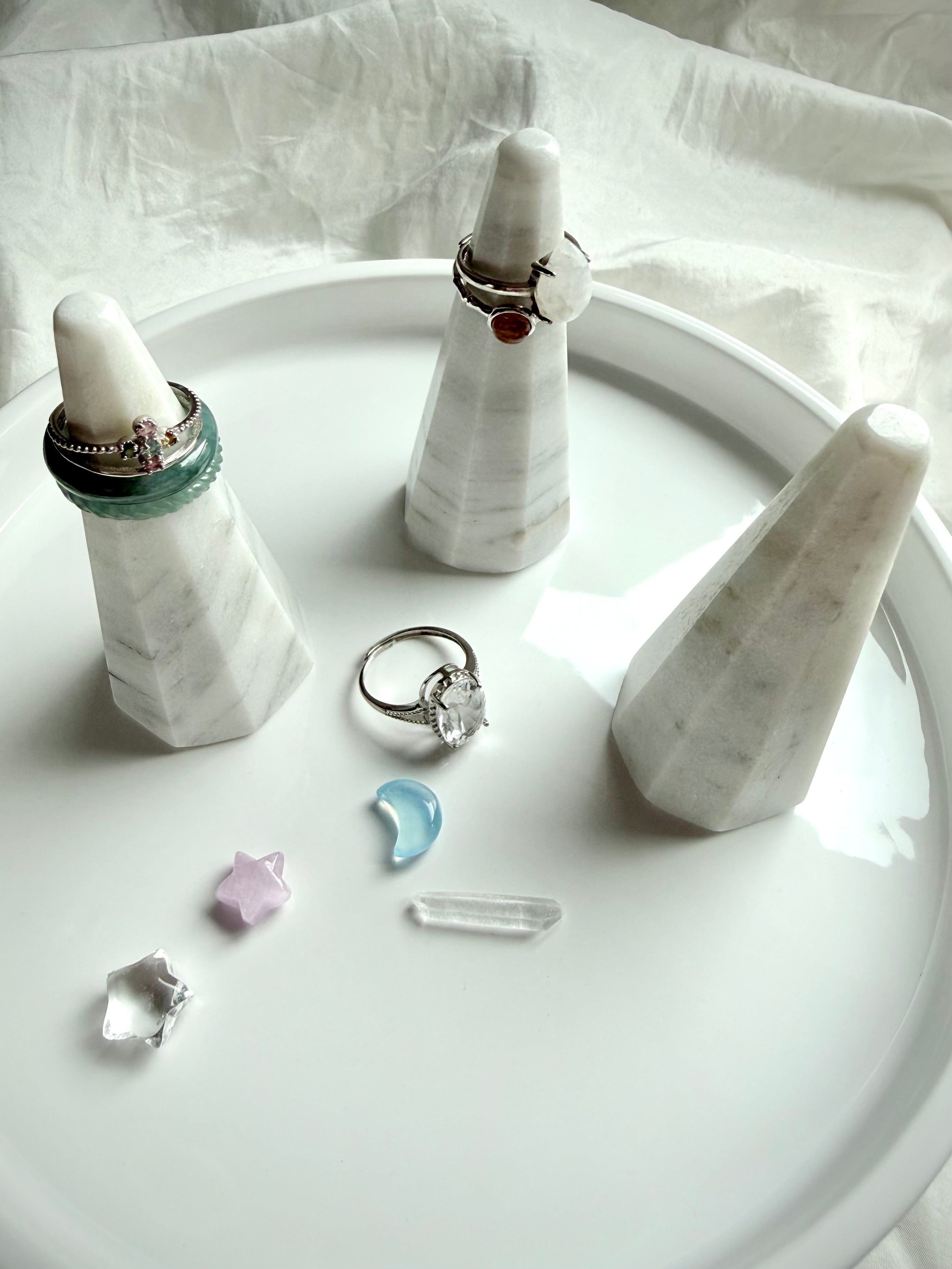 Faceted white and gray marble ring holder stand styled with stacked rings on modern jewelry display