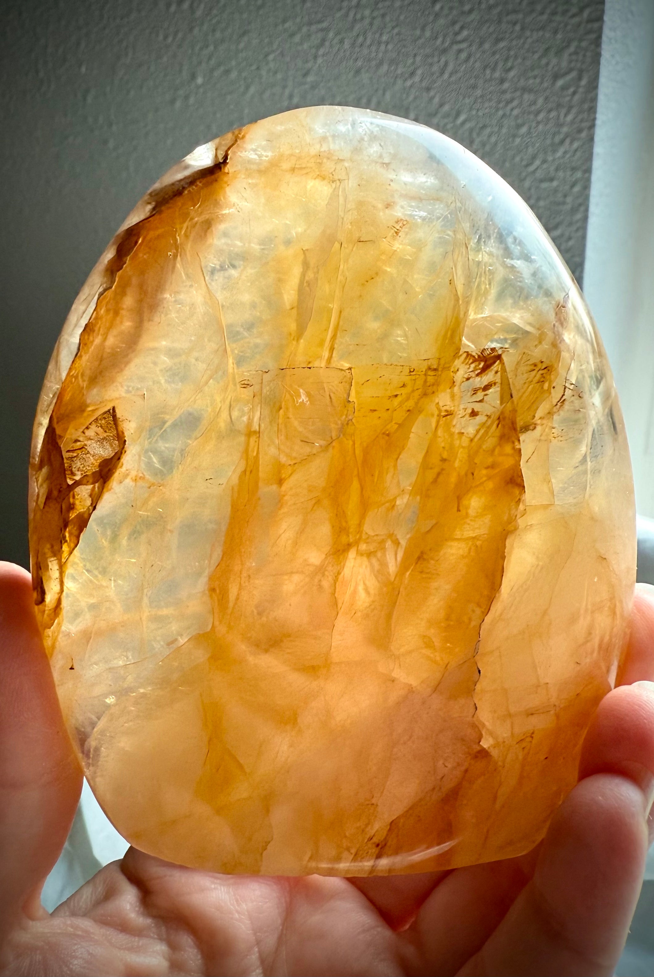 Golden Healer Quartz crystal sculpture held to the light showing translucent golden tones