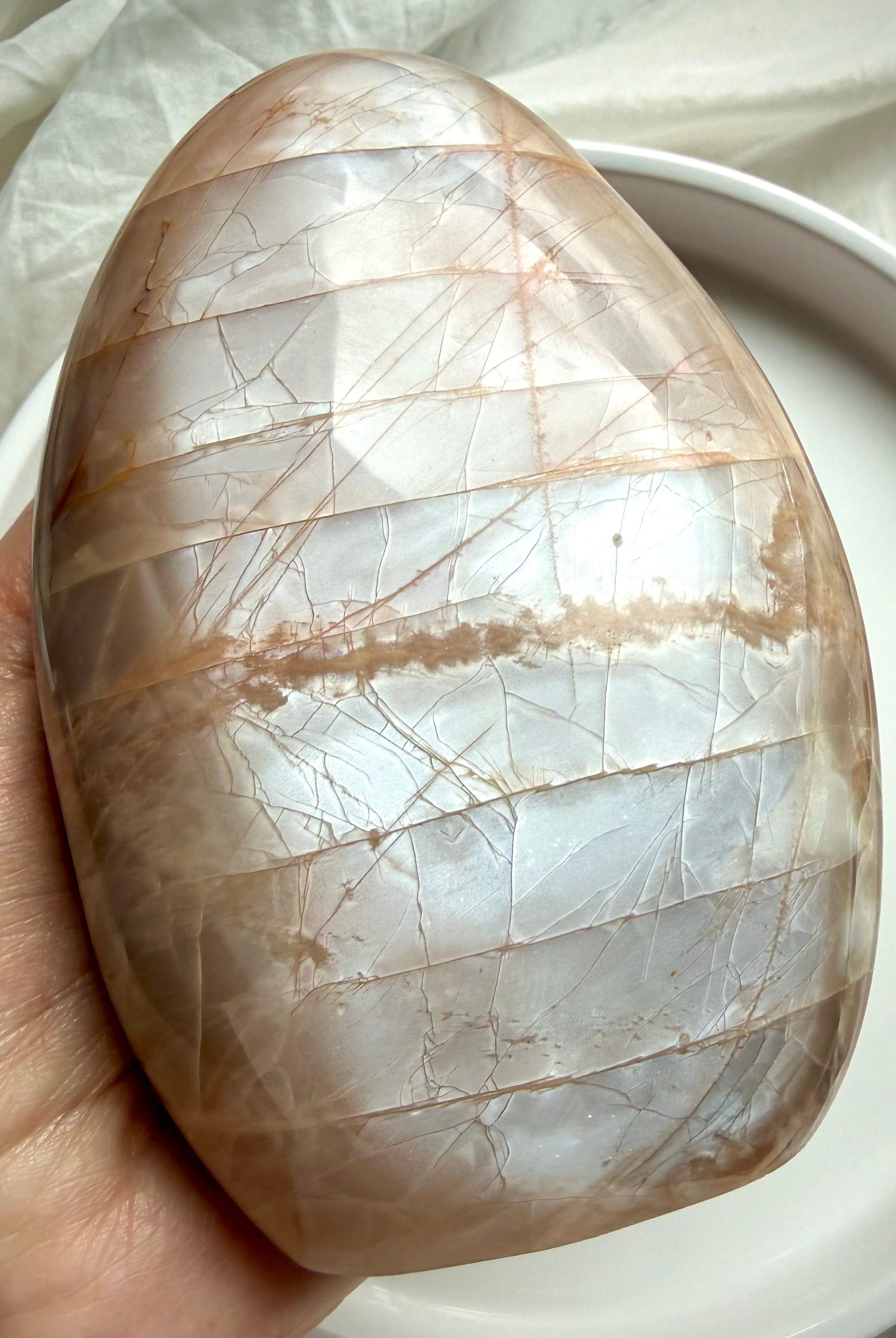 Peach Moonstone freeform crystal showing bright silvery flash in natural lighting during hand display
