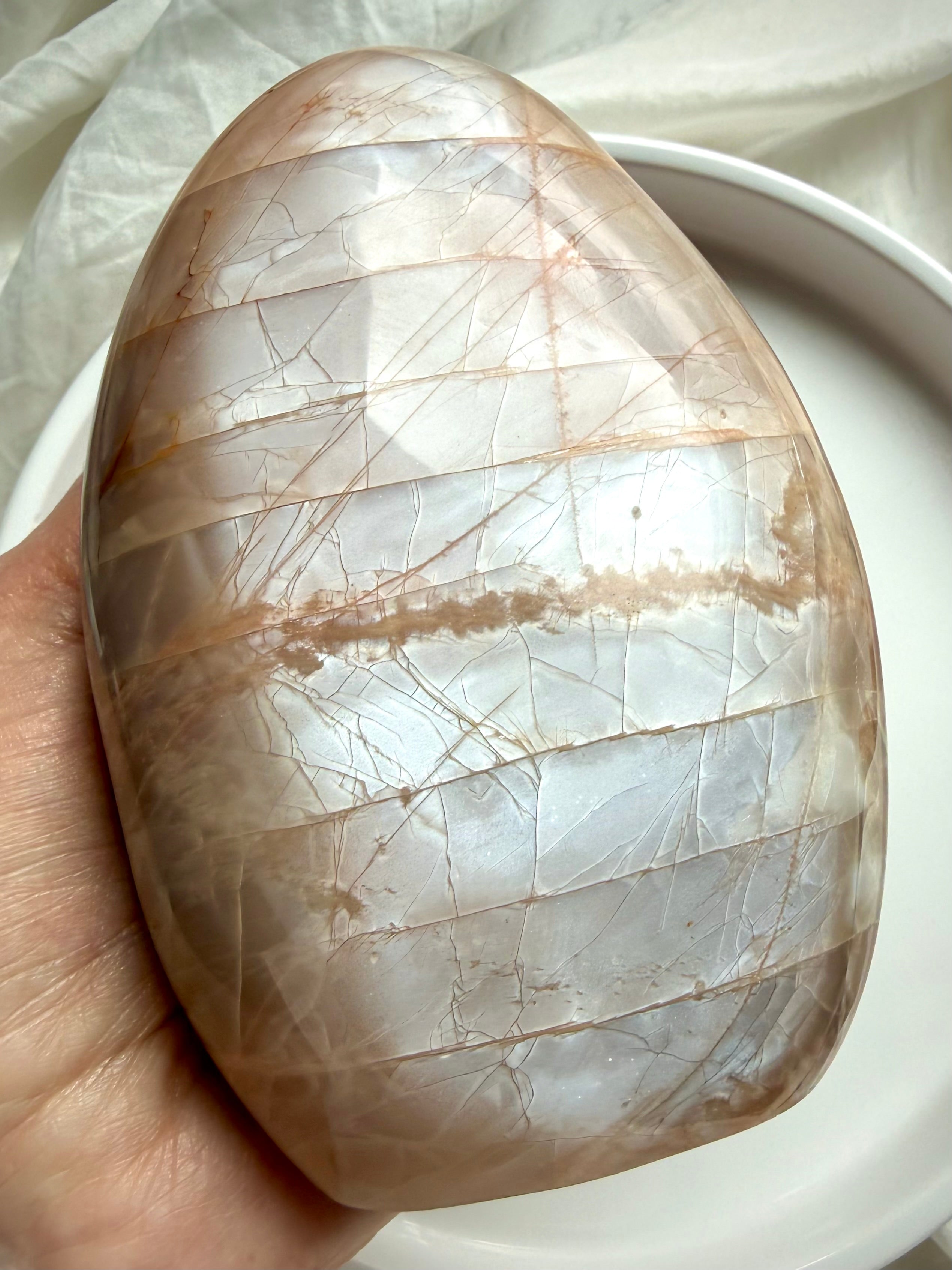 Peach Moonstone freeform crystal showing bright silvery flash in natural lighting during hand display