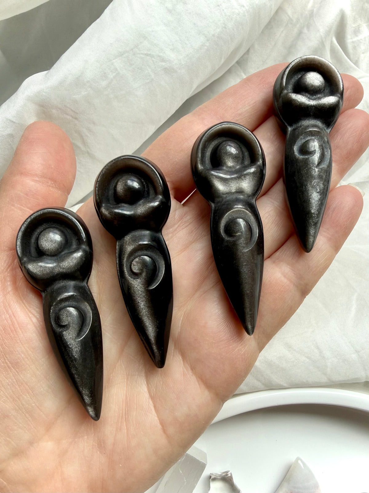 Silver Sheen Obsidian spiral goddess carvings held in hand showing natural variations in shape and silver flash