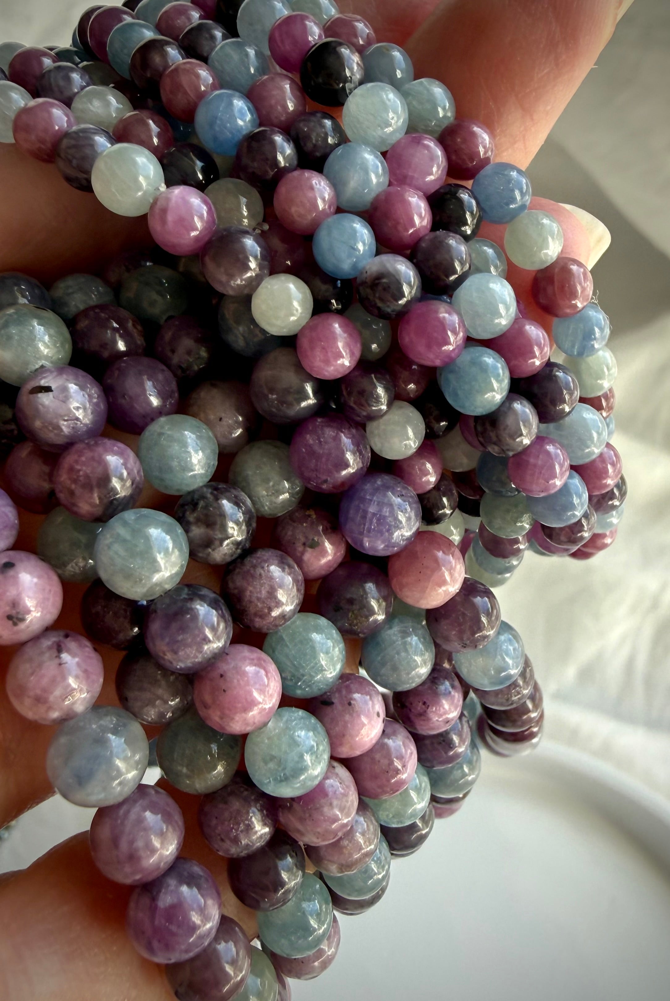 closeup of Ruby Sapphire crystal bracelets showing natural purple green and pink gemstone beads