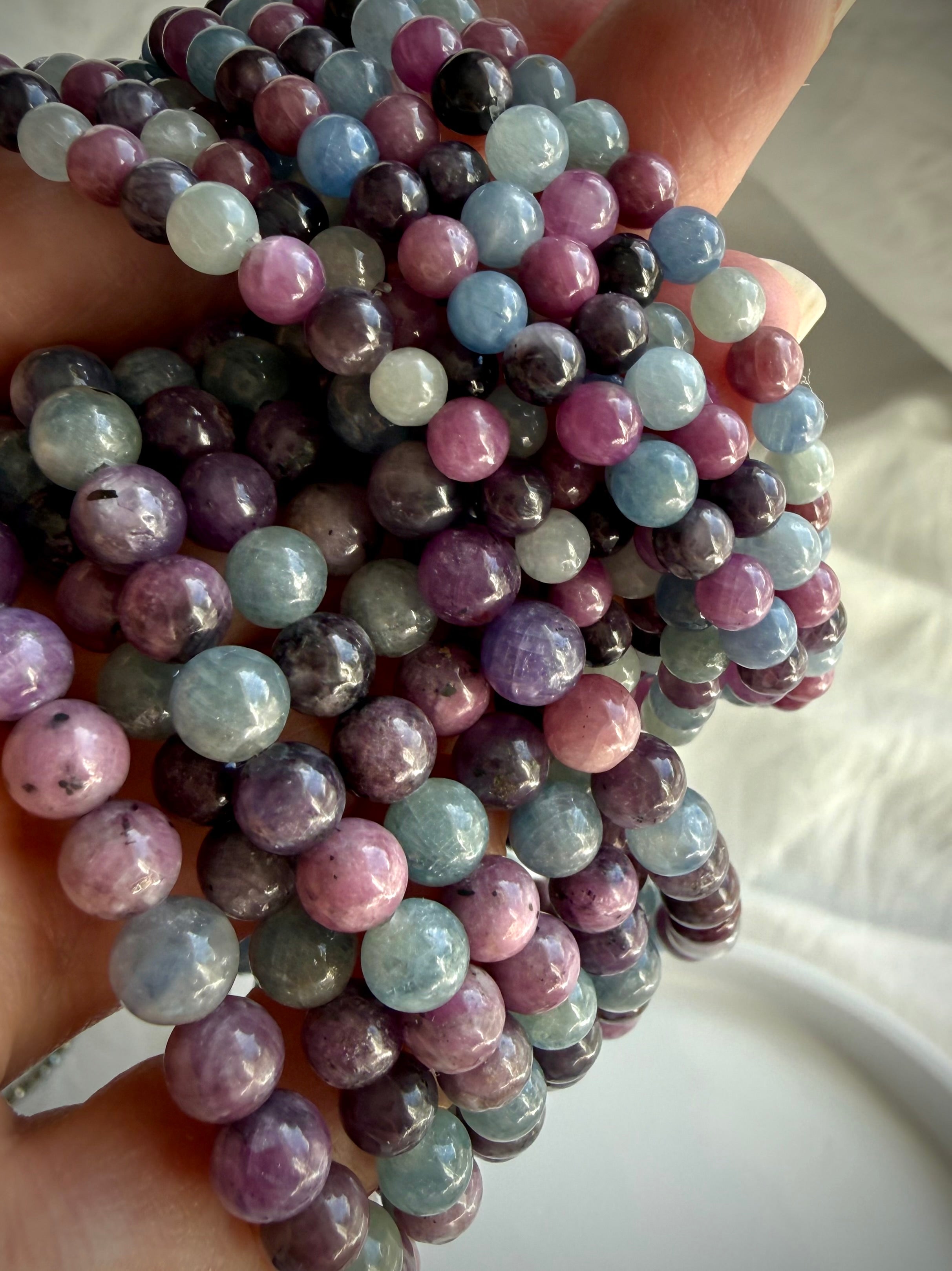 closeup of Ruby Sapphire crystal bracelets showing natural purple green and pink gemstone beads