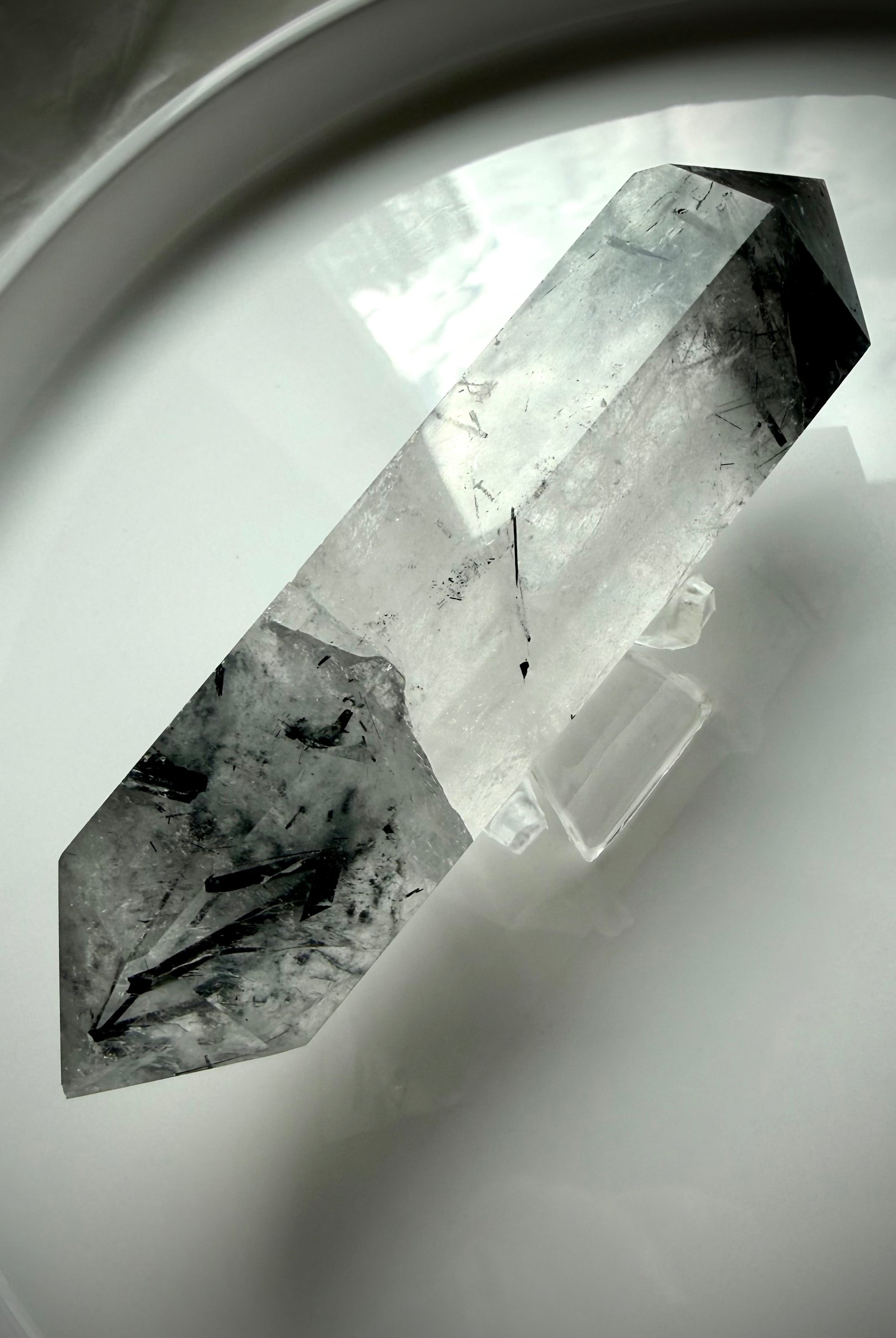 tourmalinated quartz DT crystal on white tray with soft natural lighting
