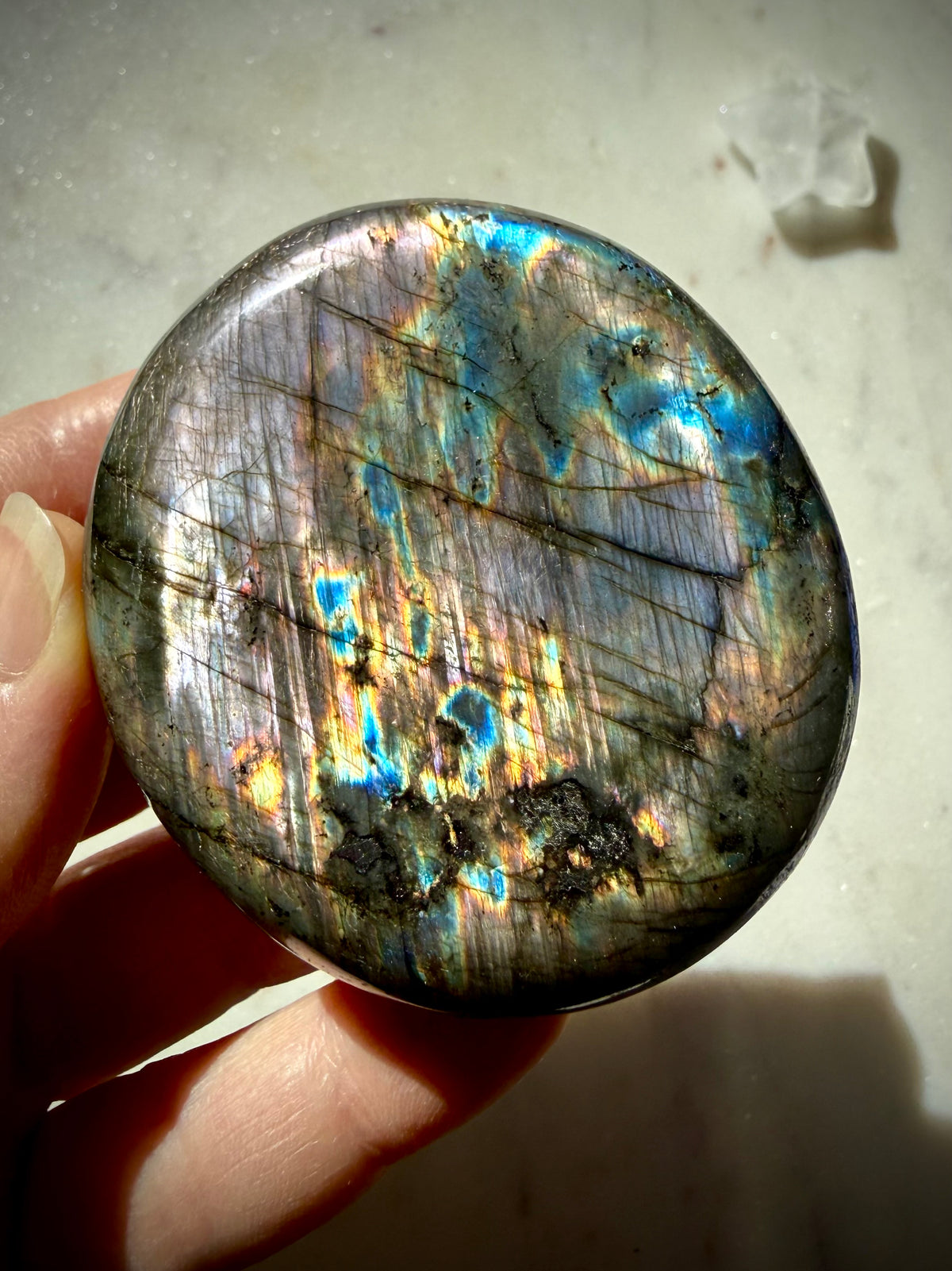 Labradorite palm stone with vivid blue, aqua and gold labradorescence shifting across natural silver flash matrix
