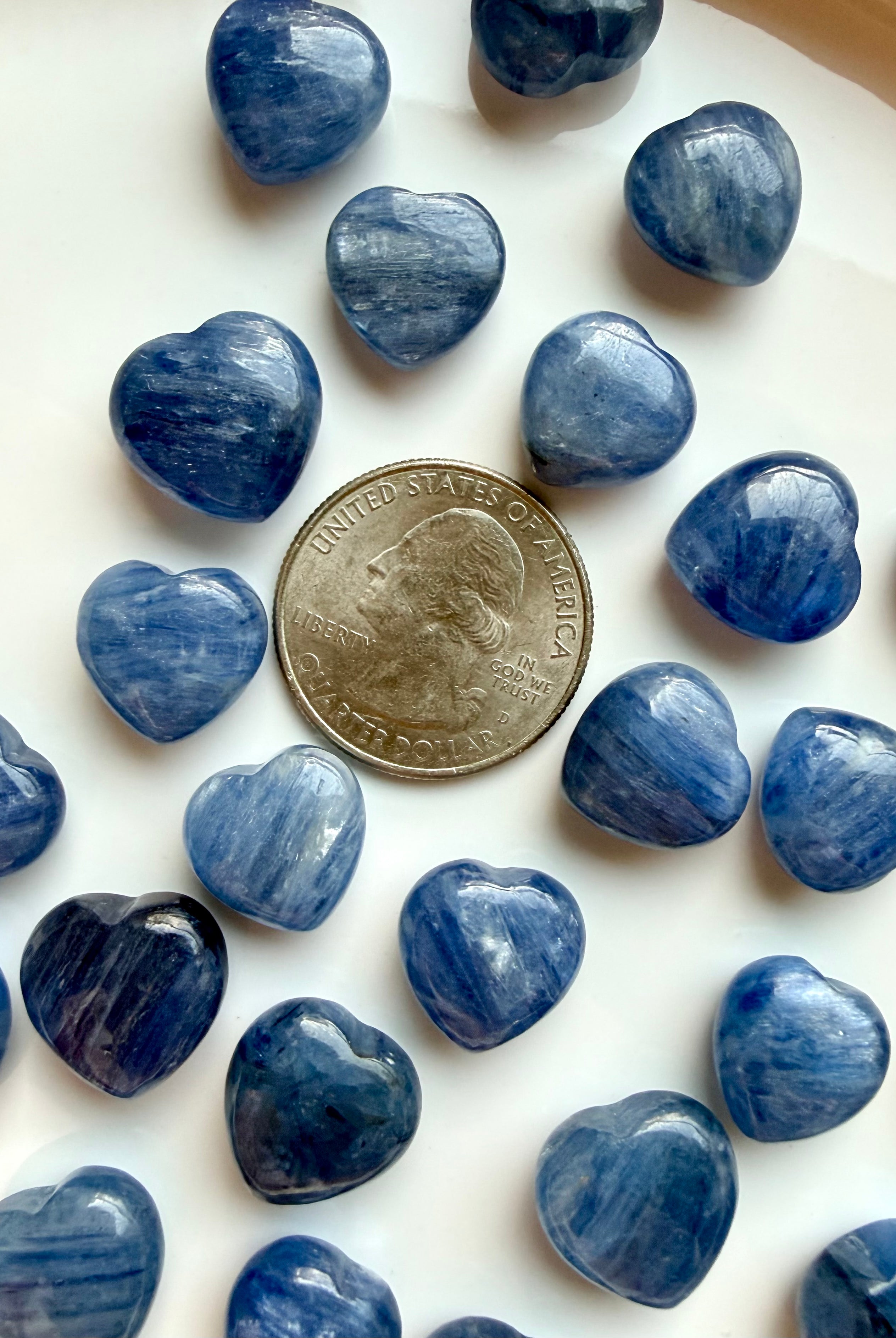 Mini Blue Kyanite heart crystals shown beside a US quarter for size reference, polished silvery blue throat chakra stones for meditation and crystal grids