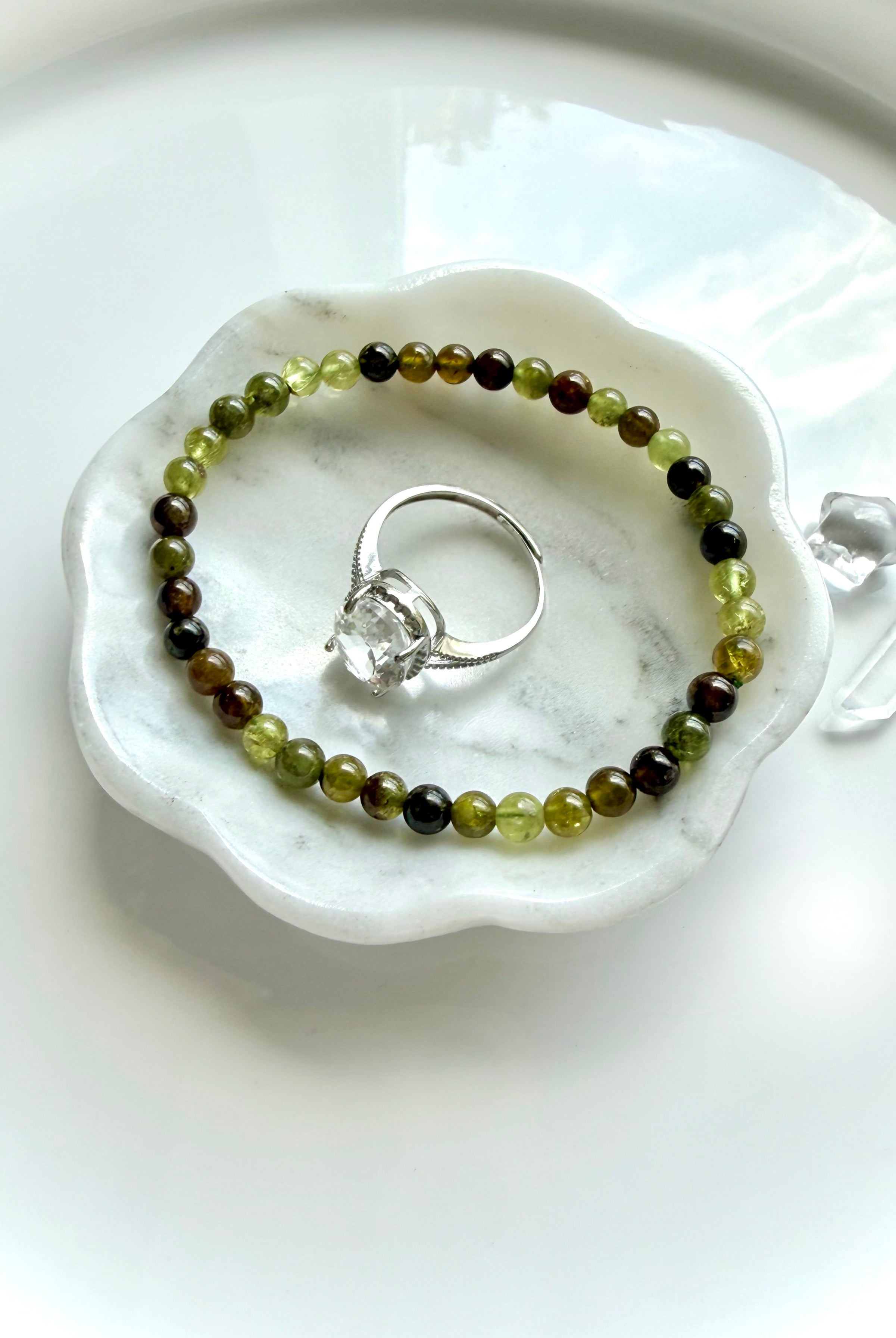 Tsavorite Garnet crystal bracelet shown with a gemstone ring in a marble jewelry dish, vanity table styling