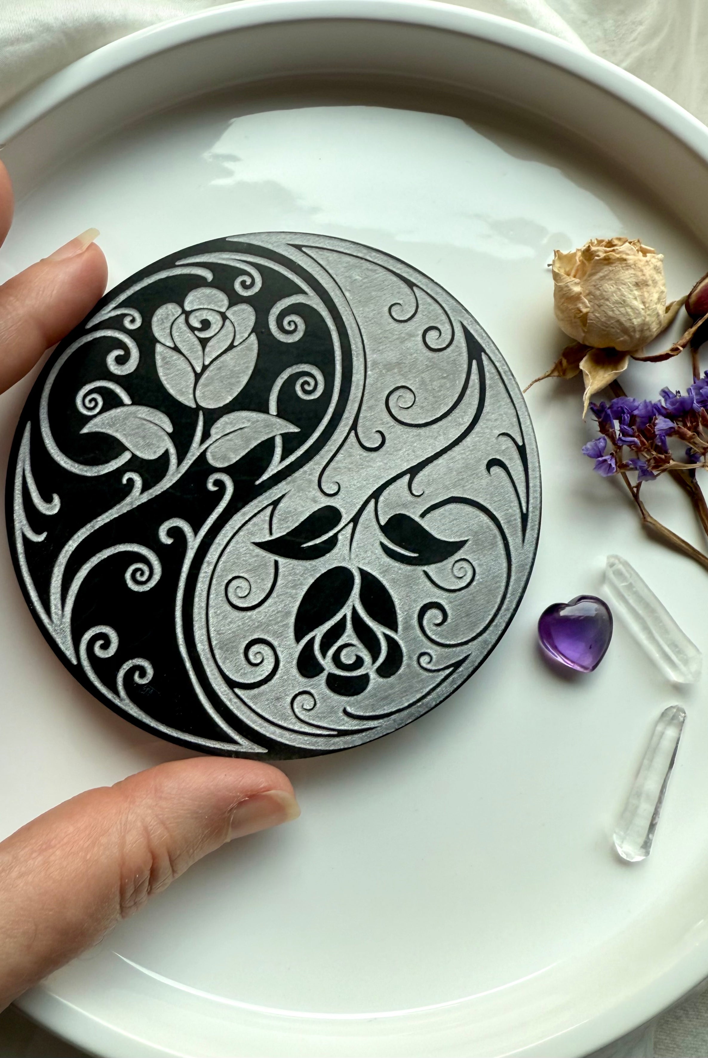 Yin yang rose selenite plate surrounded by dried flowers, amethyst, and clear quartz points for energy rituals