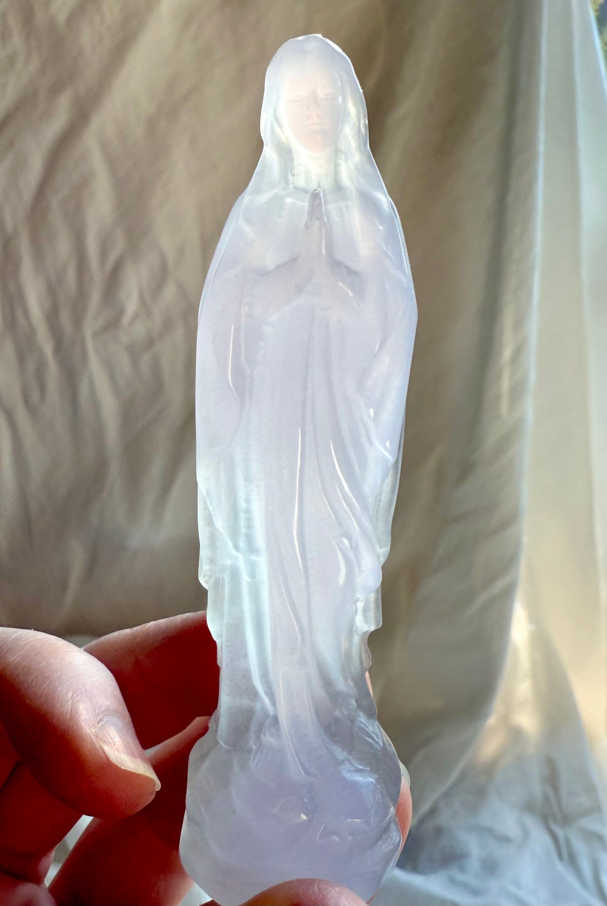 Yttrium Fluorite Mother Mary carving held in hand, a luminous Divine Mother crystal statue for grace and protection