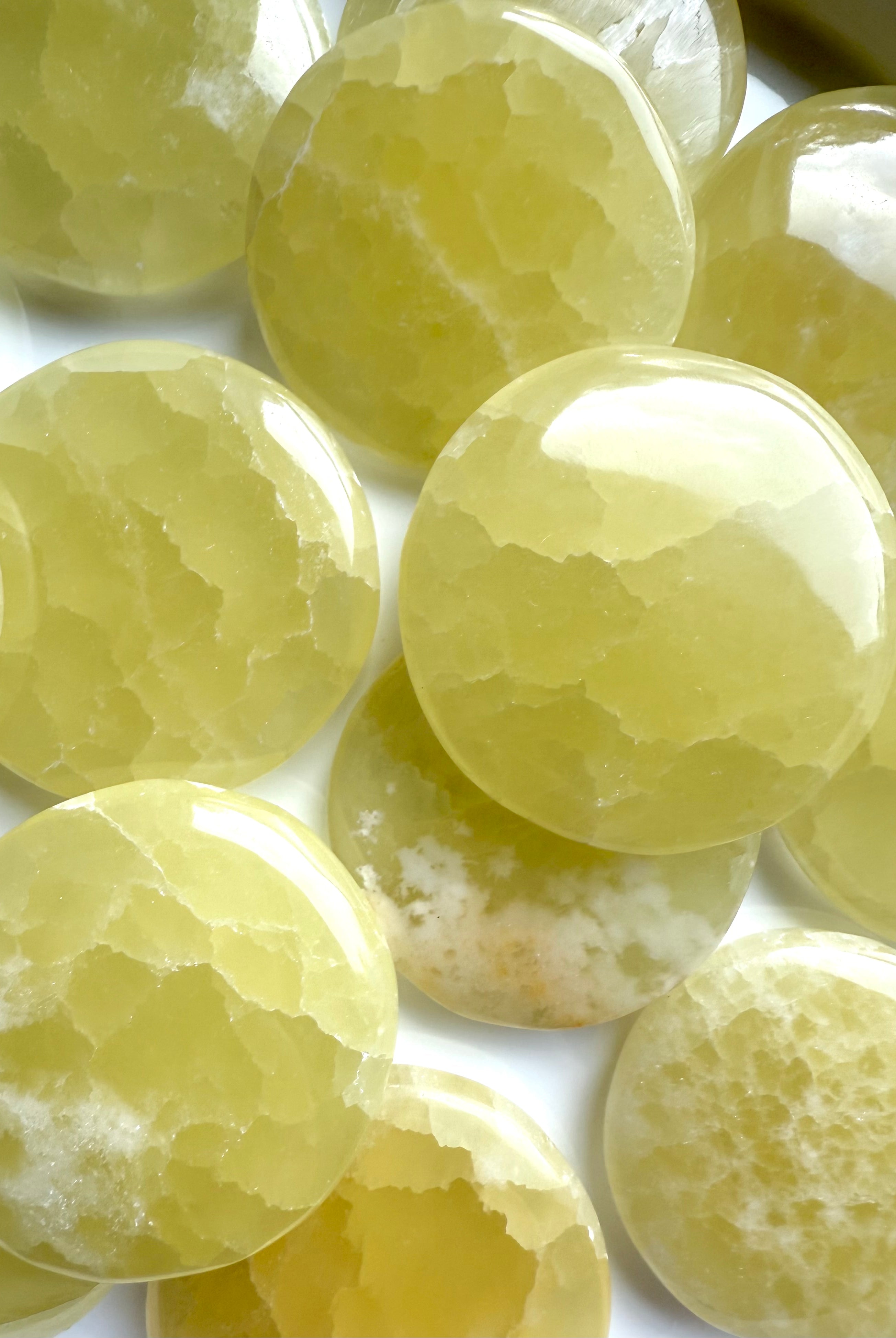 Close-up of lemon calcite palm stones with a mix of milky and crystalline patterns
