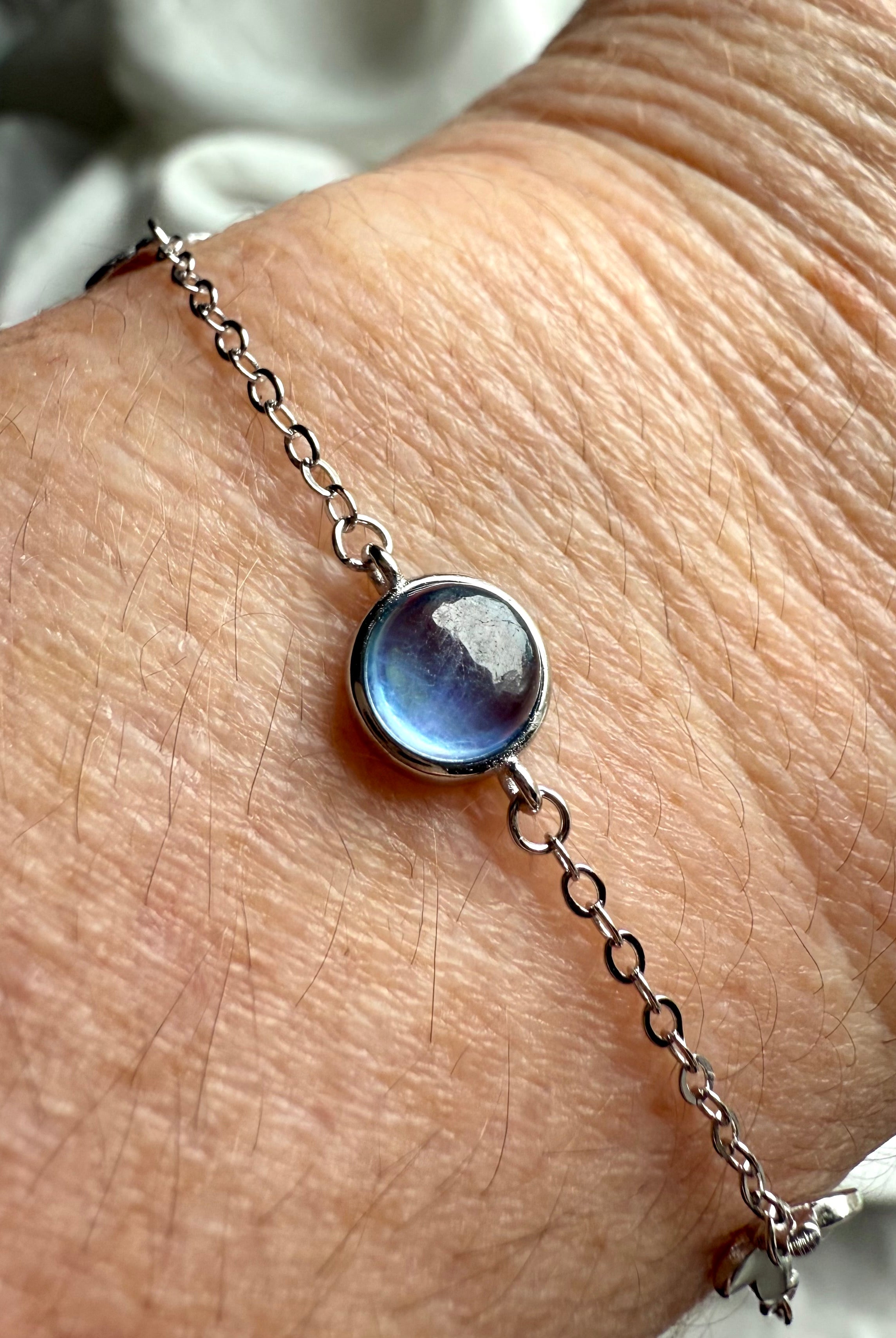 Close-up of sterling silver aquamarine bracelet on wrist, handmade gemstone jewelry for peace, clarity, and emotional balance