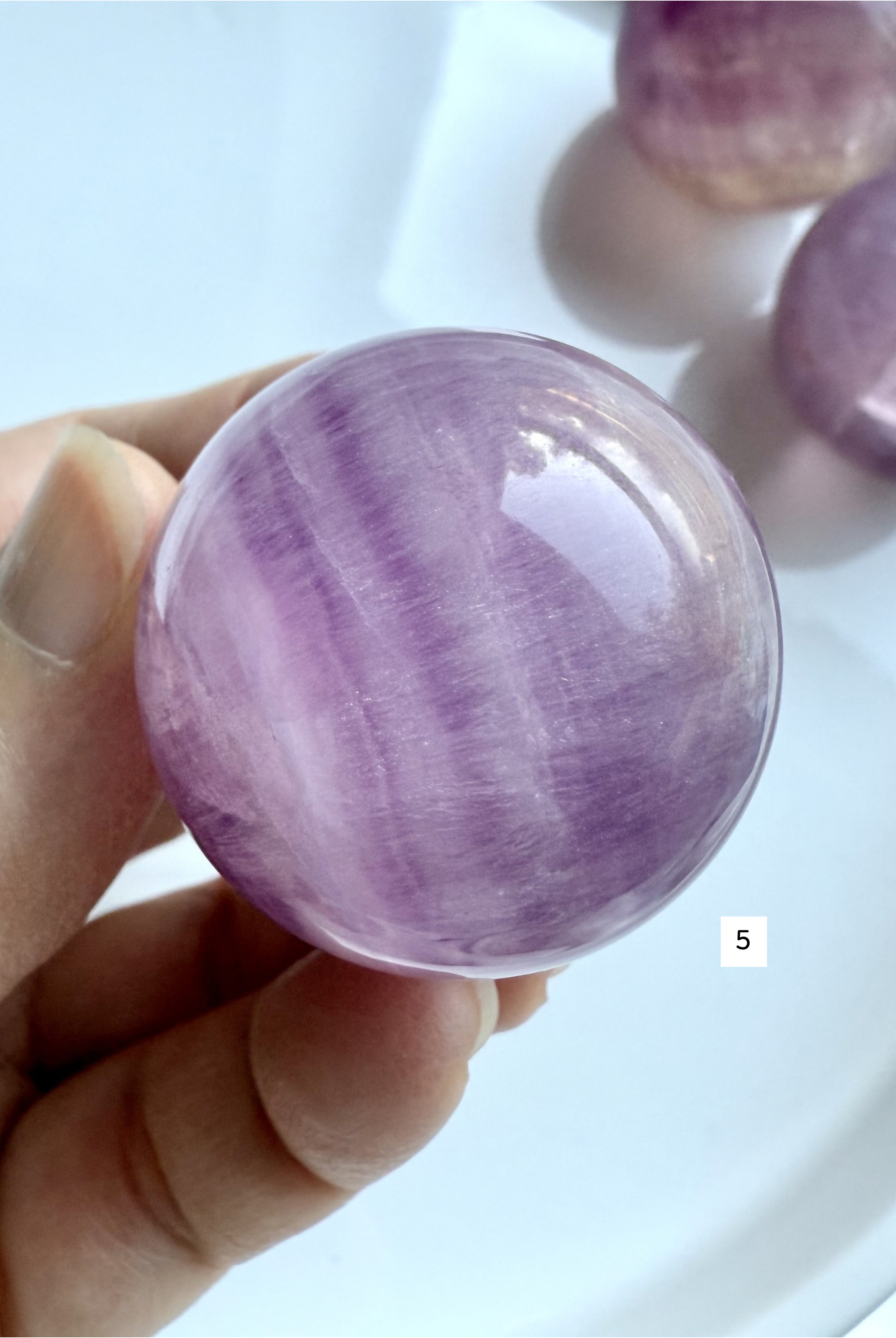 rare pink and purple Fluorite sphere with natural silky banding and polished glossy finish held in hand
