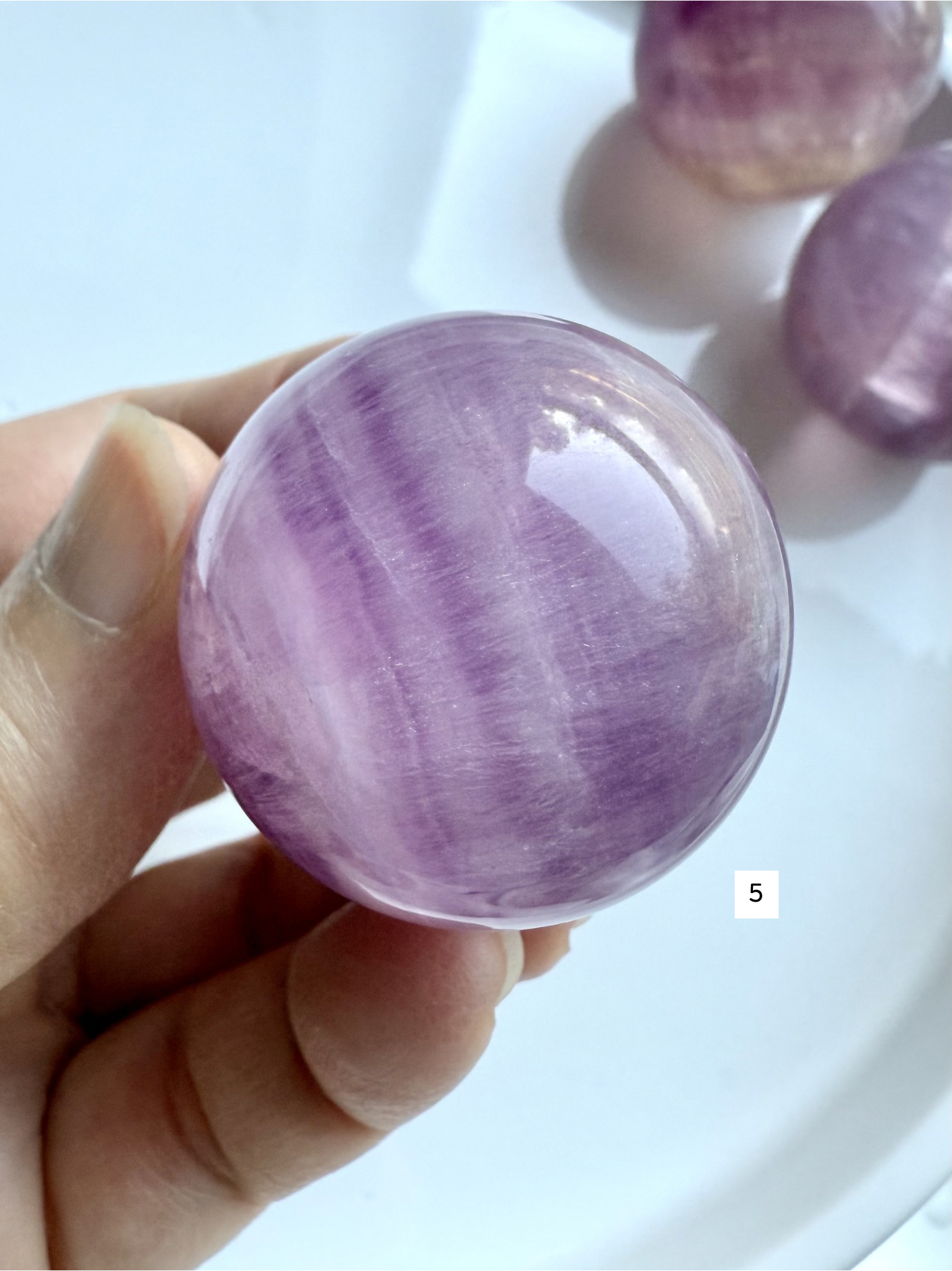 rare pink and purple Fluorite sphere with natural silky banding and polished glossy finish held in hand
