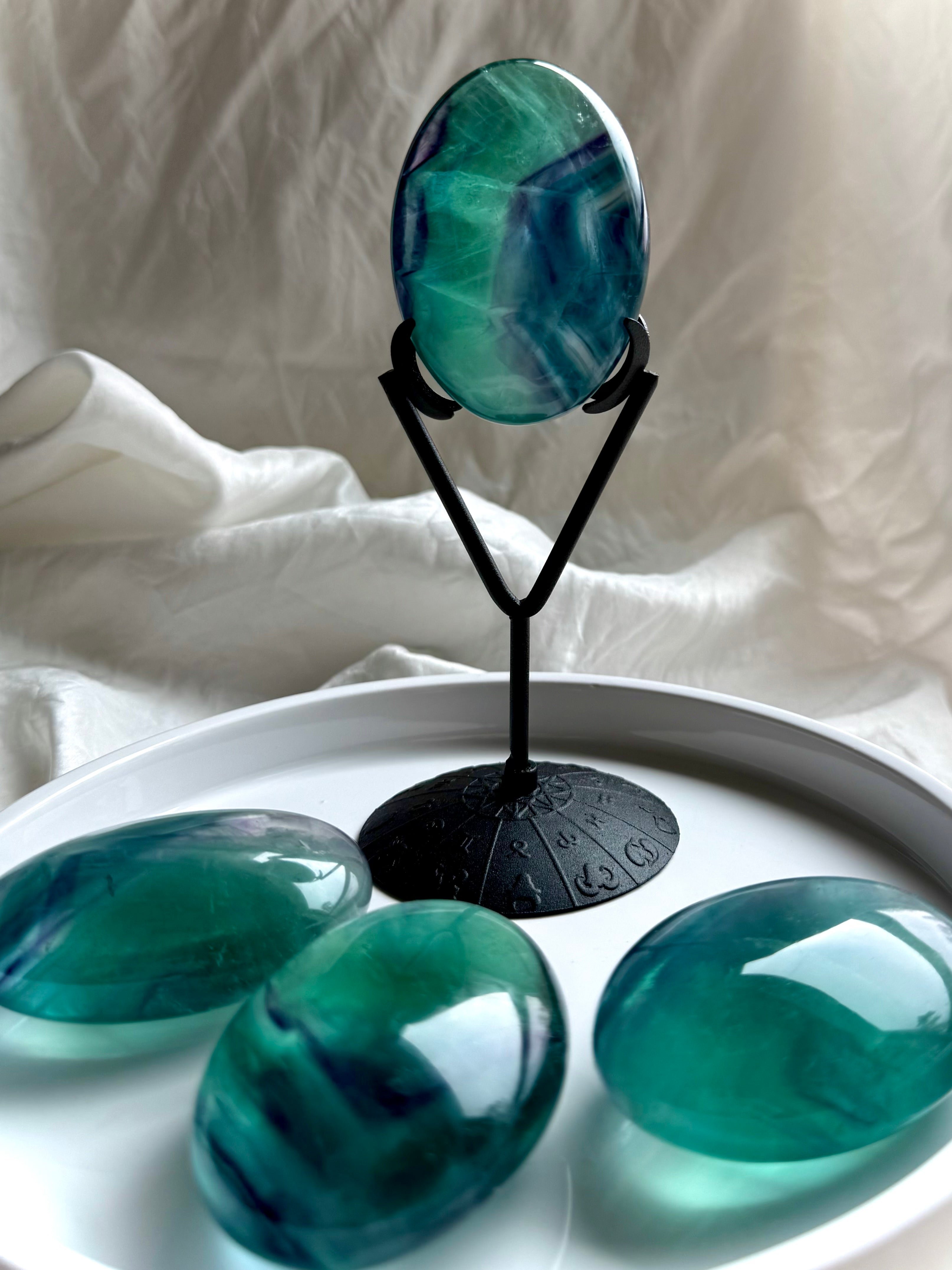 Large banded teal fluorite palm stone displayed on stand with oceanic blue green color and translucent depth