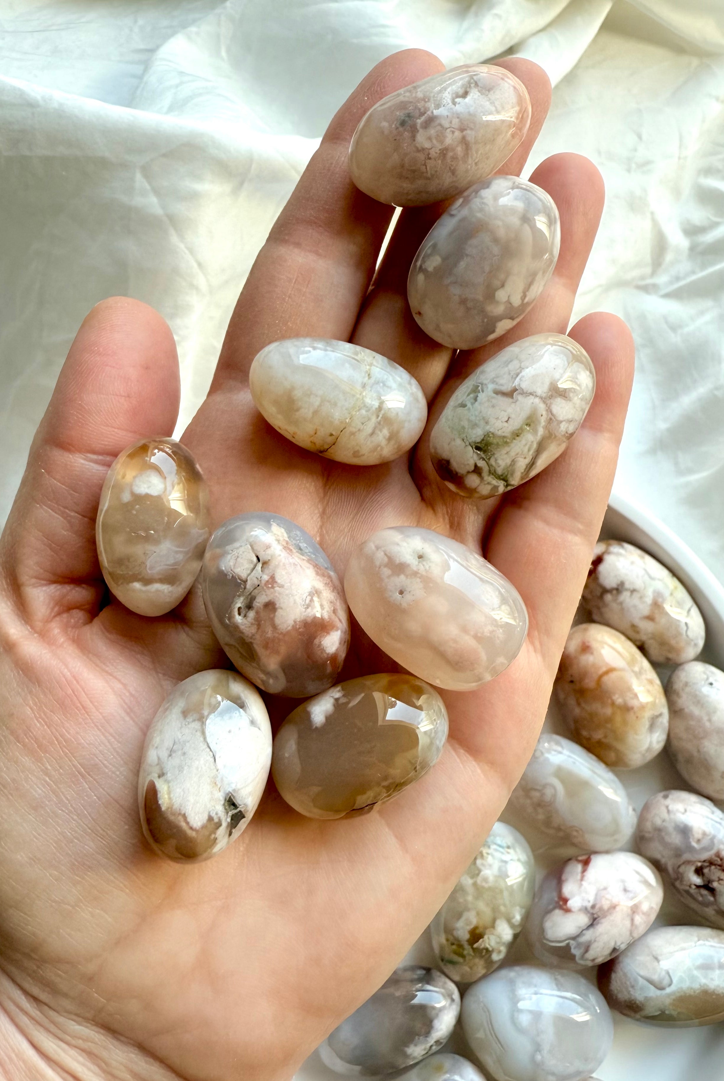 High quality Flower Agate tumbled stones with pastel color patterns shown on a hand for scale