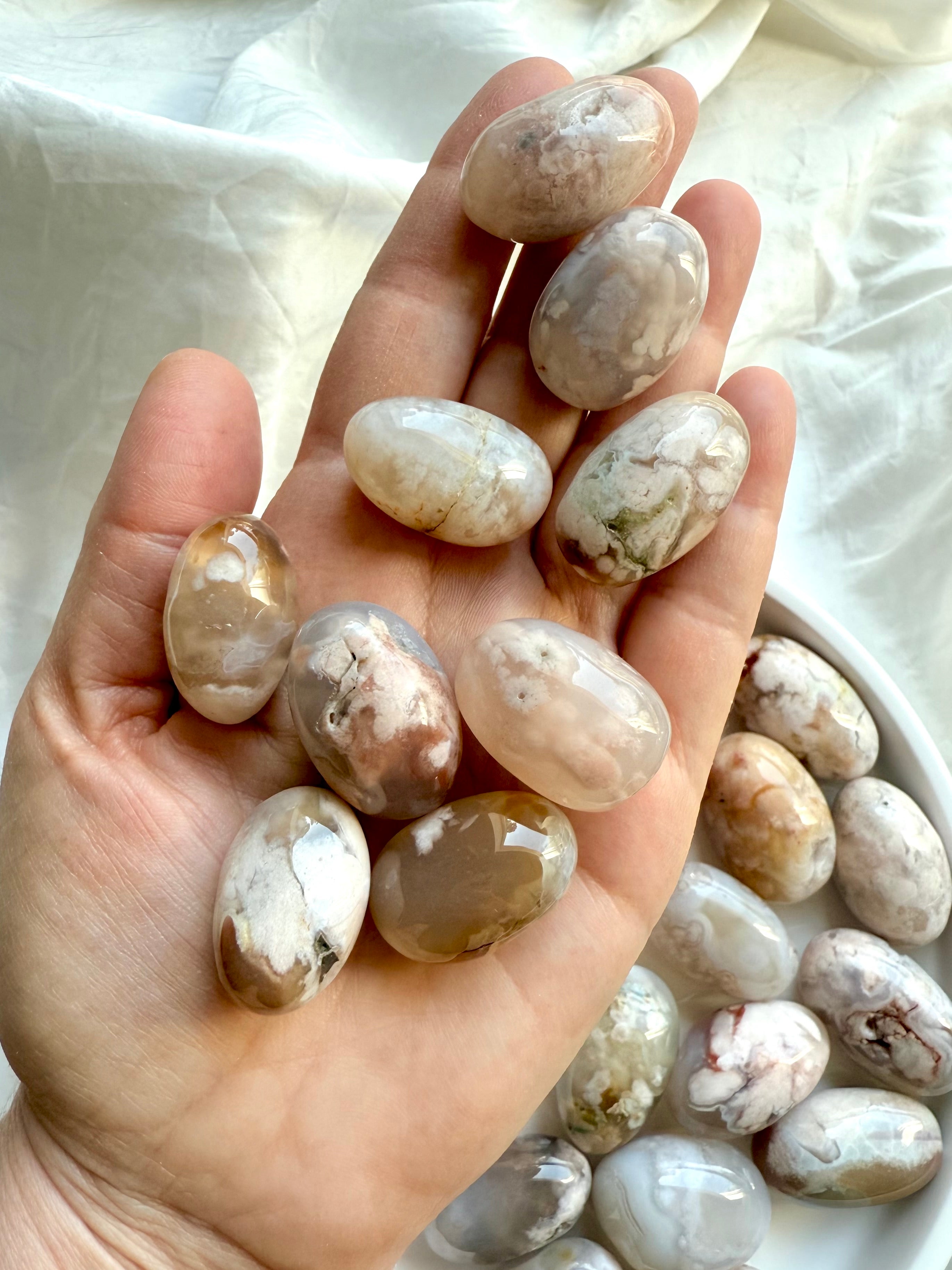 High quality Flower Agate tumbled stones with pastel color patterns shown on a hand for scale