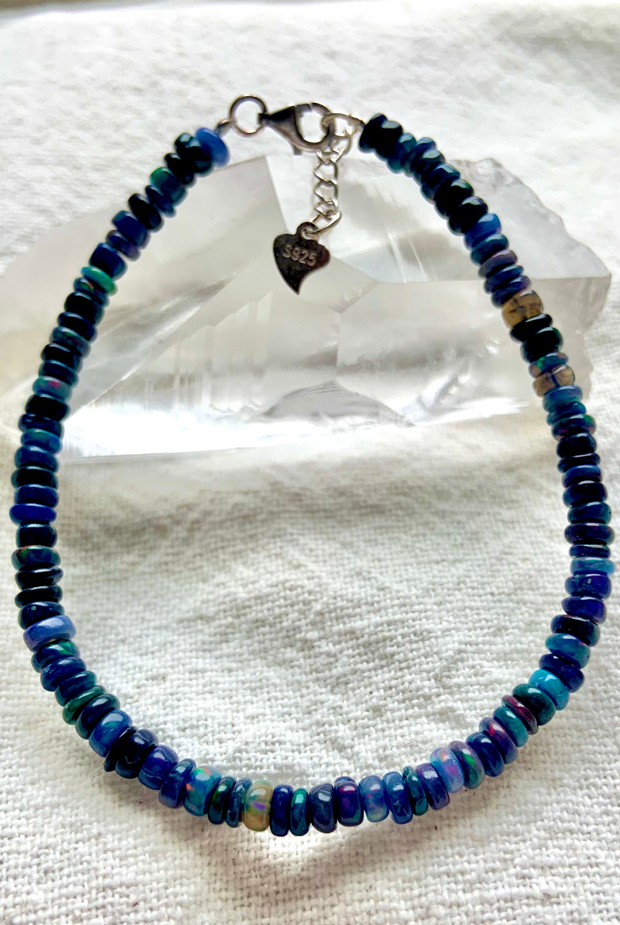 Black Fire Opal bracelet over a quartz point showing S925 stamp on heart-shaped extender — sterling silver Ethiopian opal jewelry detail.