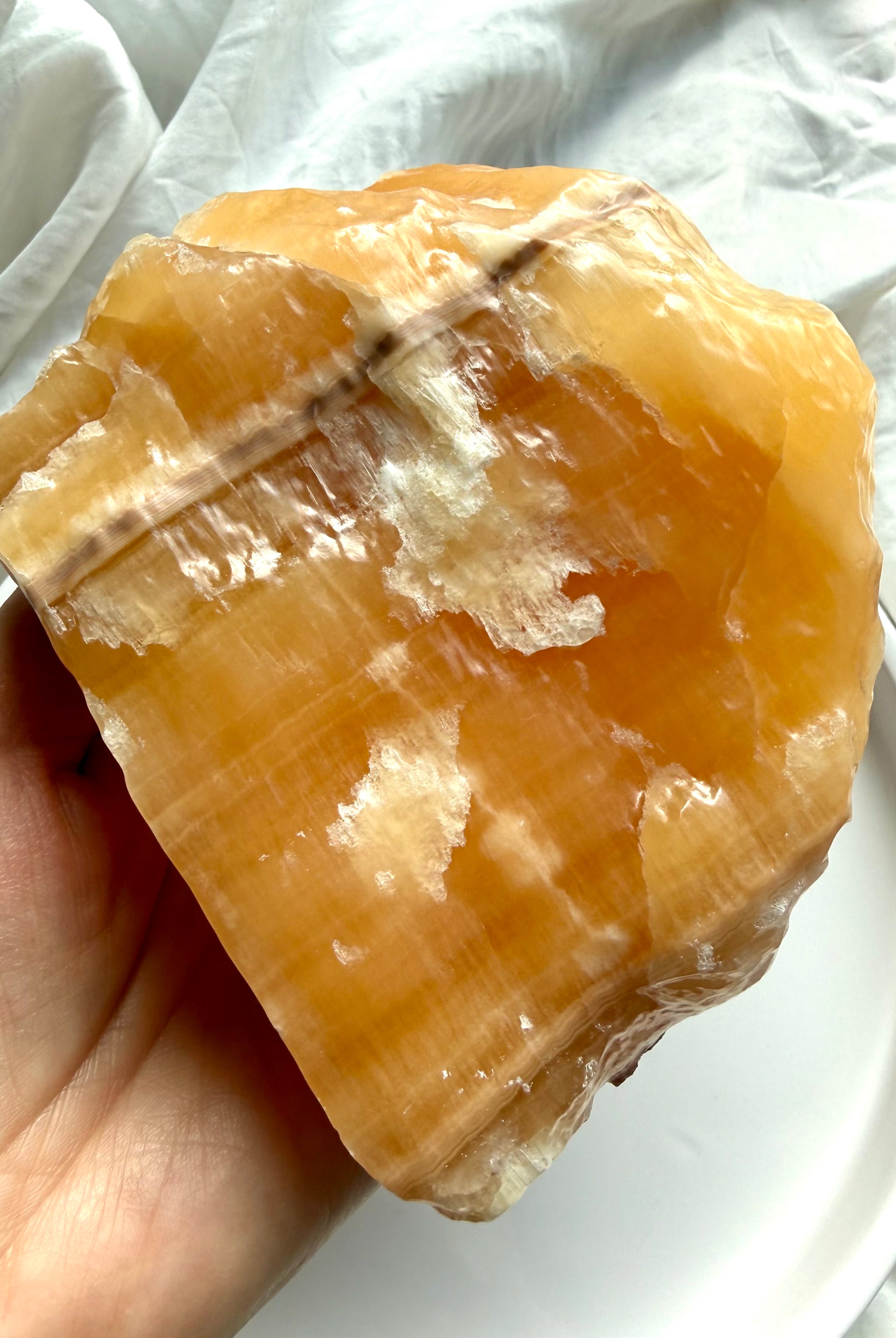 Large Orange Calcite mineral display specimen with natural texture, white calcite formations, and warm orange glow