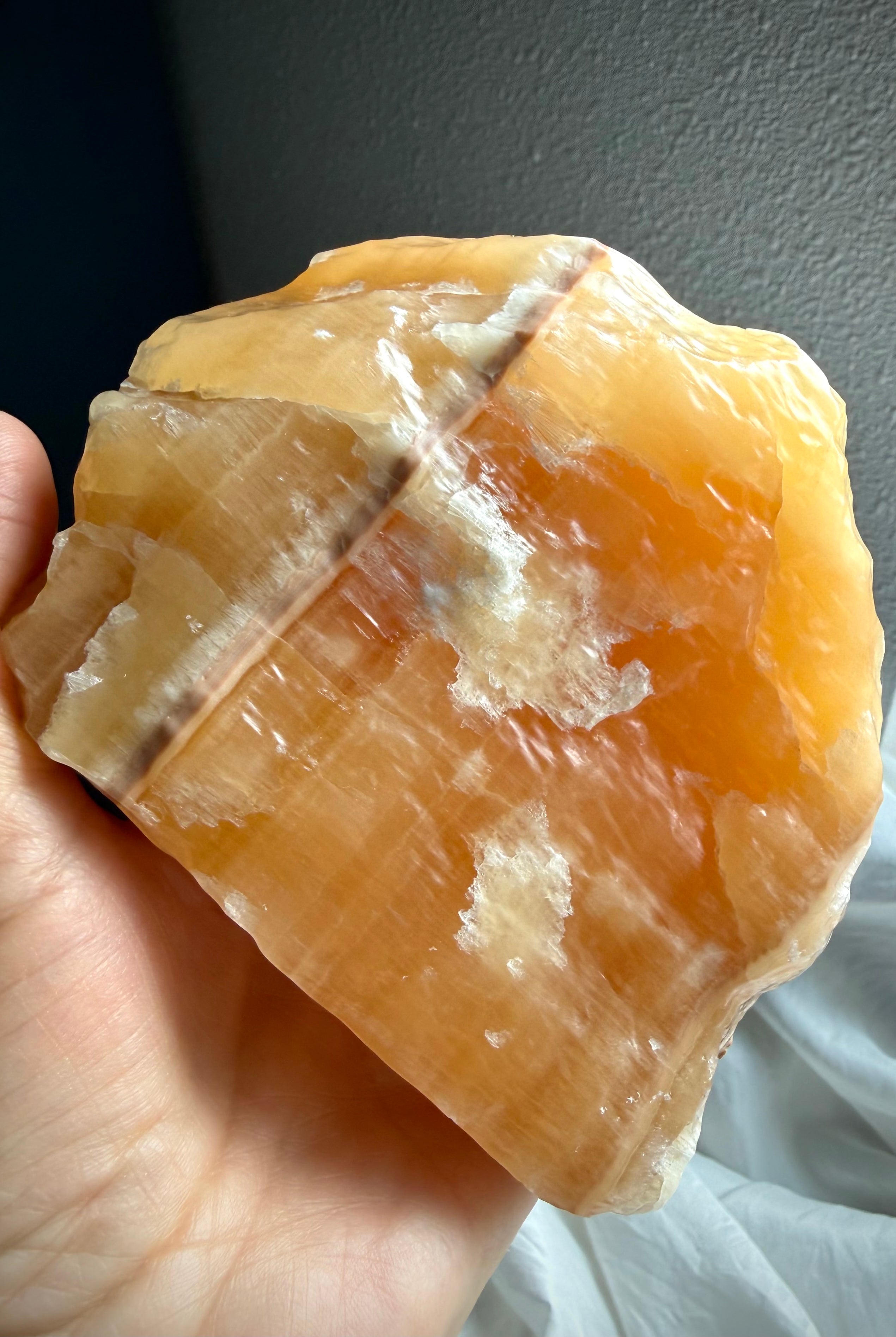 Handheld Orange Calcite statement piece showing raw crystal texture, vibrant orange color, and natural mineral structure