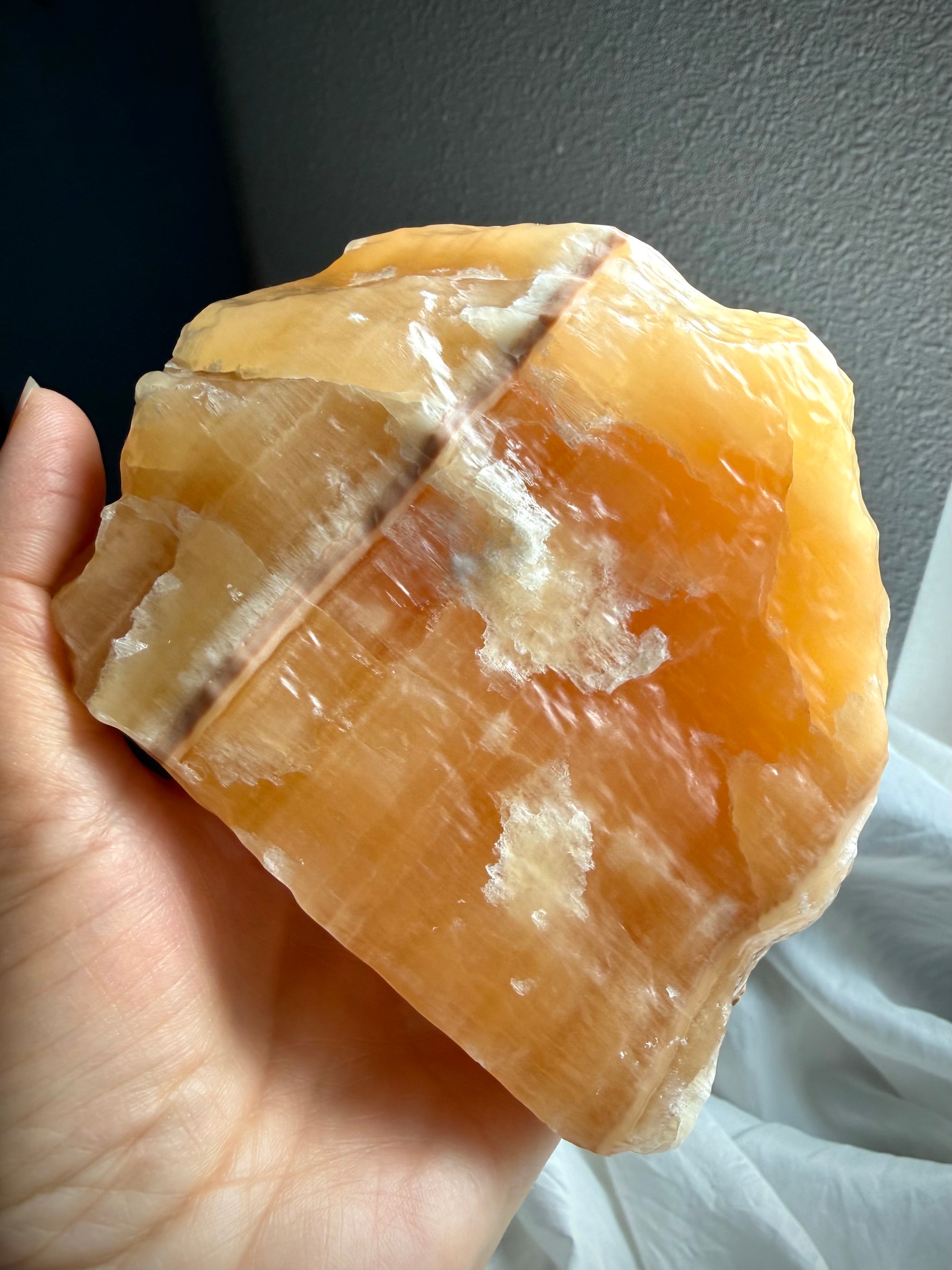 Handheld Orange Calcite statement piece showing raw crystal texture, vibrant orange color, and natural mineral structure