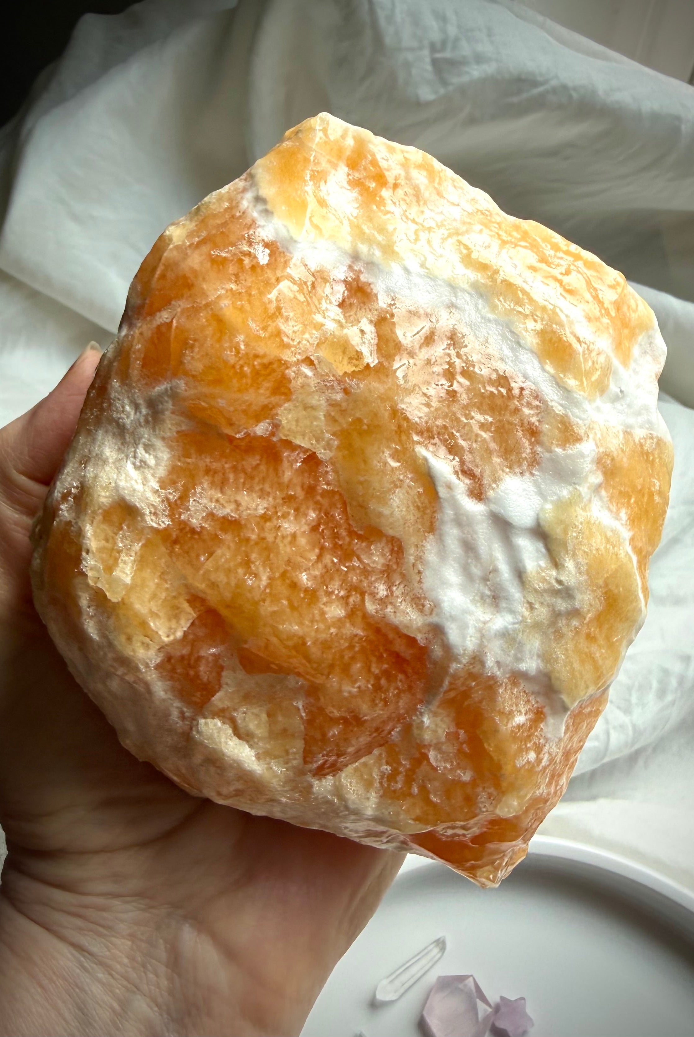Handheld Orange Calcite crystal from Mexico with raw yet refined texture and glowing interior color
