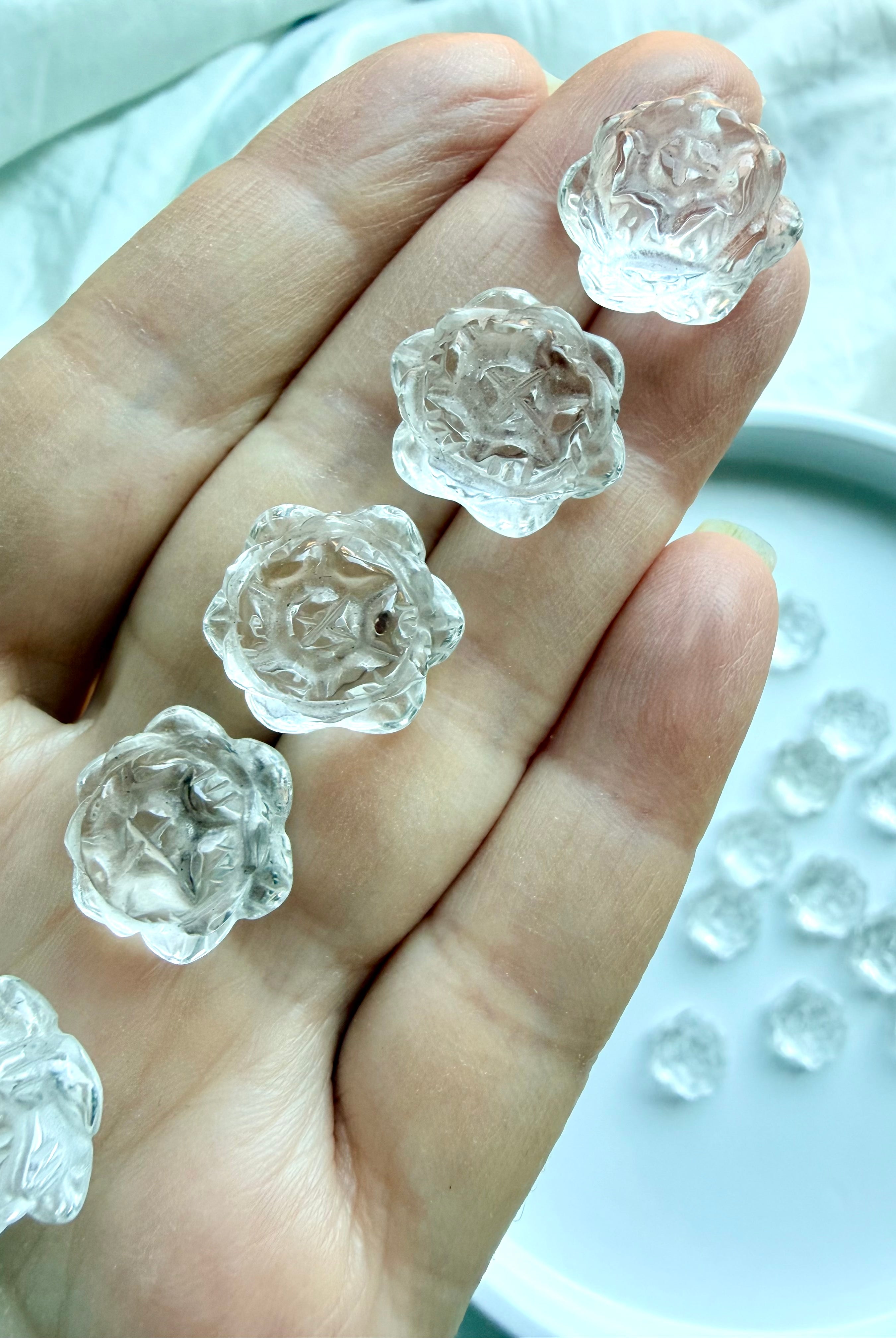 Closeup of mini Clear Quartz lotus flower crystals held in hand, tiny polished carvings for pocket stones, crystal grids and gifts