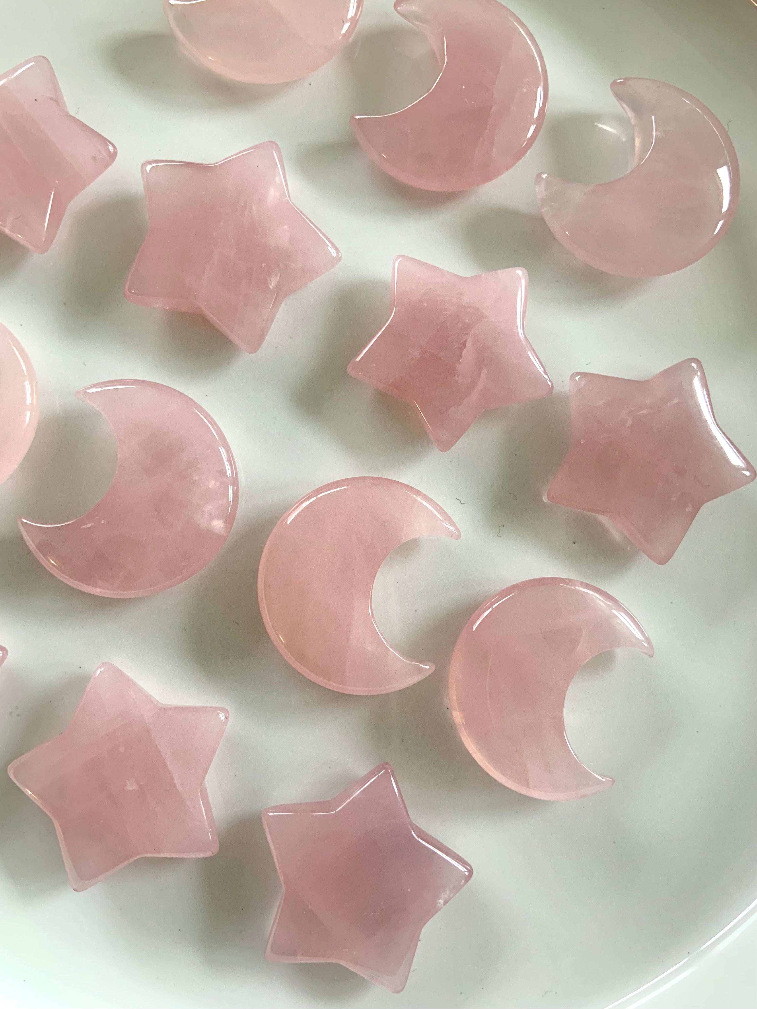 Rows of rose quartz moons and stars on white. Madagascar rose quartz carvings for unconditional love, heart healing & emotional balance.