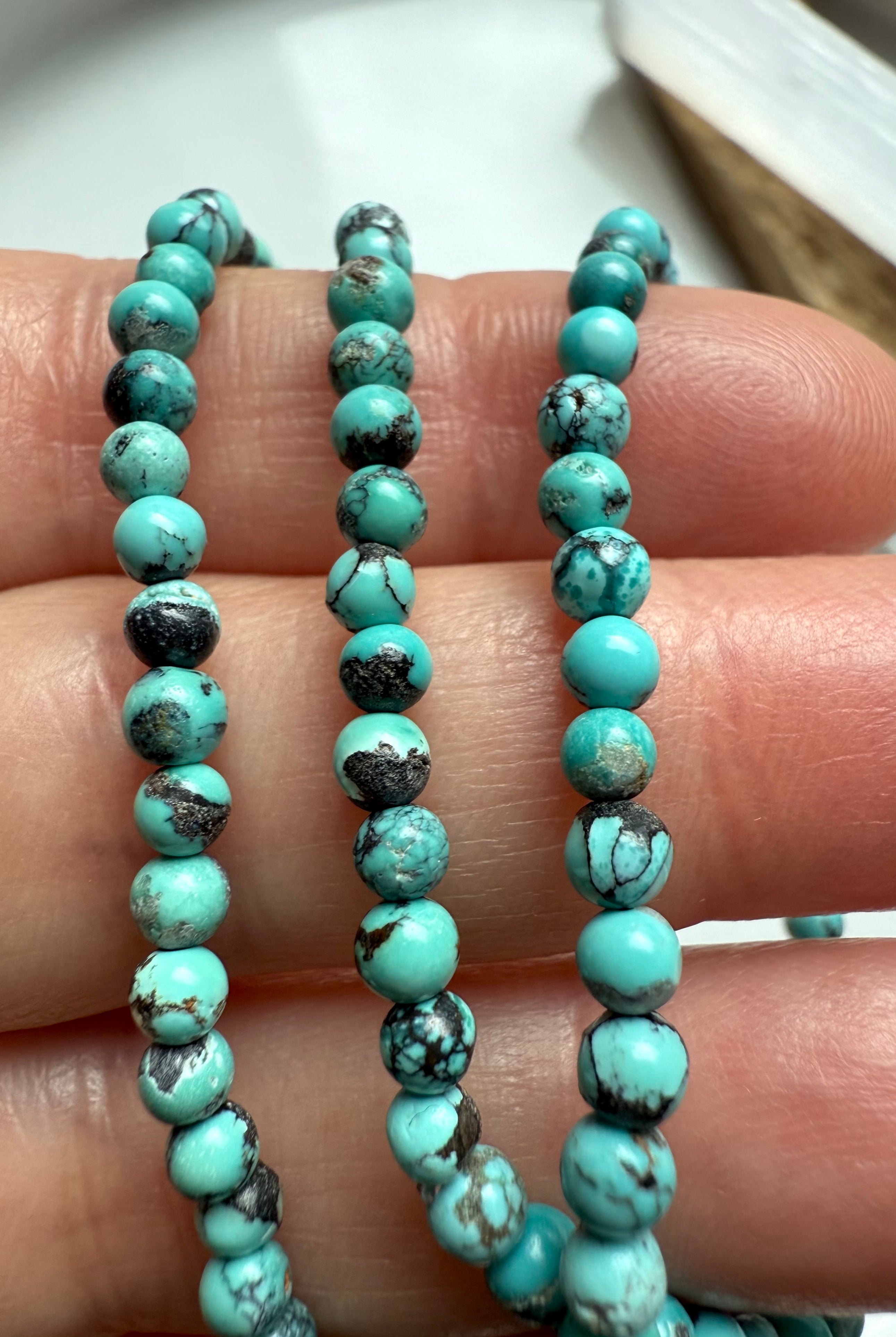 Close-up of small turquoise round beads with black matrix and natural color variation
