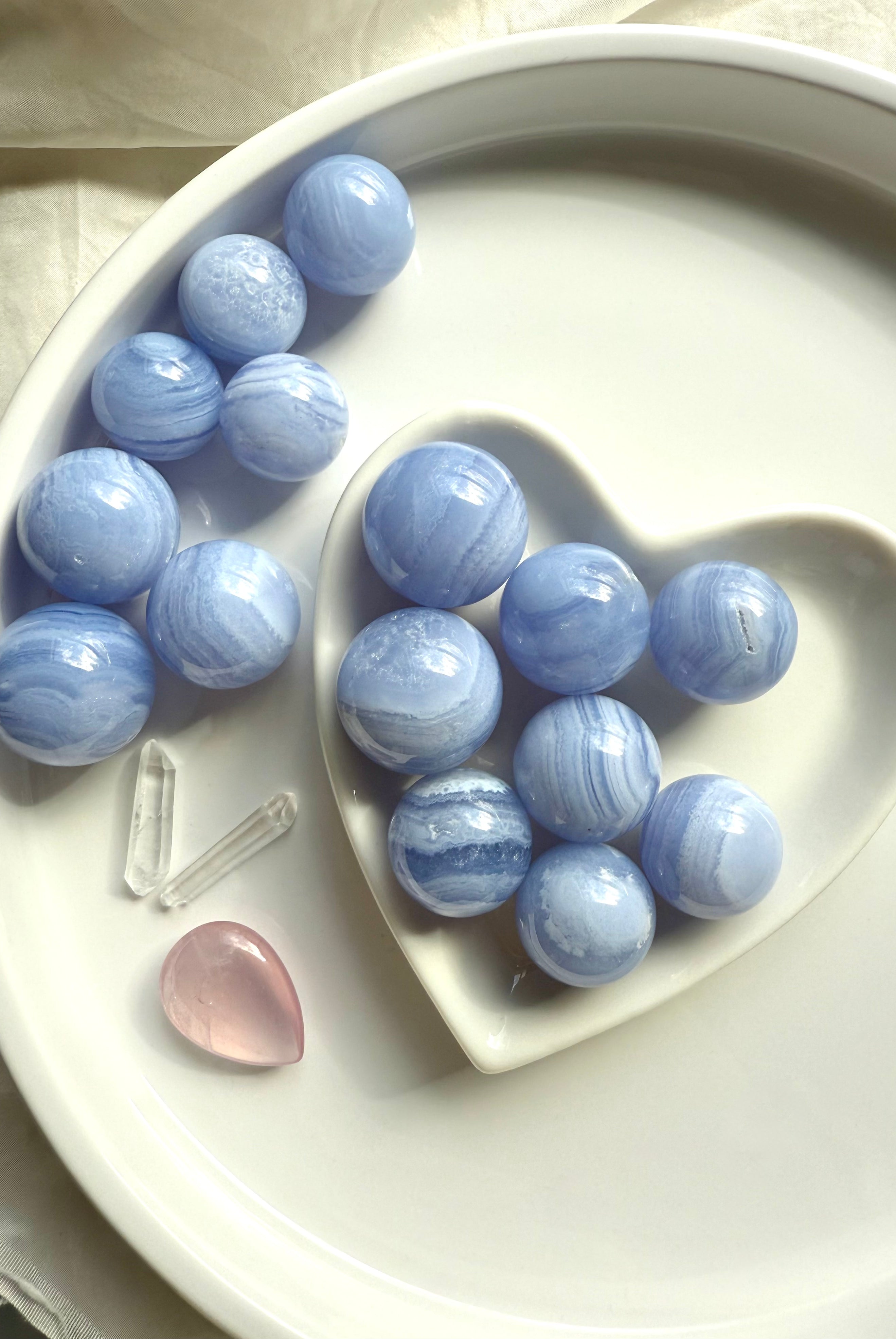 An array of mini sized high quality Blue Lace Agate Spheres on a white plate