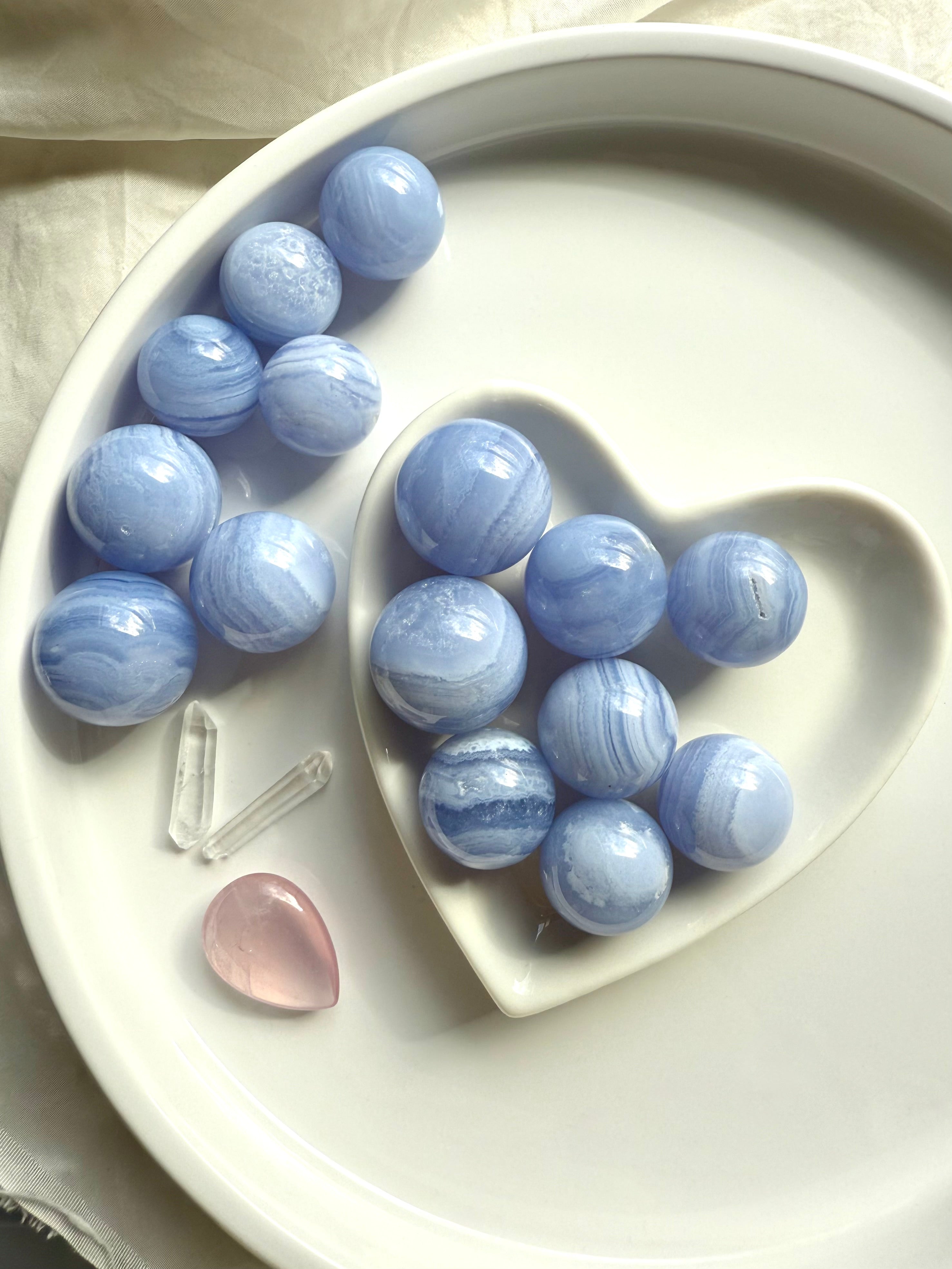 An array of mini sized high quality Blue Lace Agate Spheres on a white plate