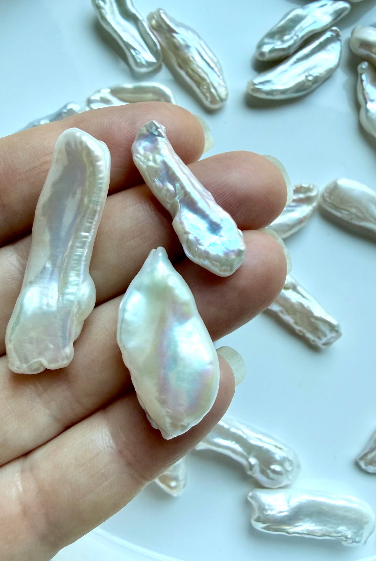 Closeup of undrilled Baroque Stick Pearls held in hand showing natural size, shape & pearlescent luster